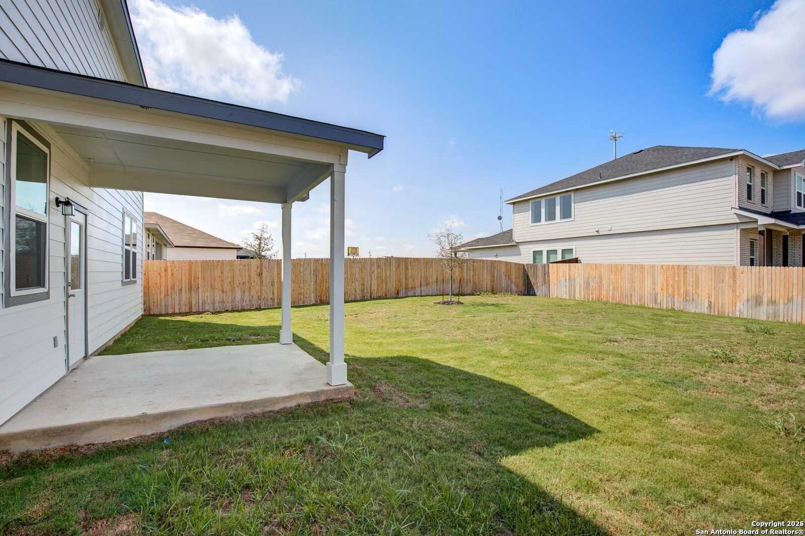 Covered back patio with lush green lawn and wooden privacy fence in Davidson Homes The Douglas B, Hannah Heights, Seguin, Texas