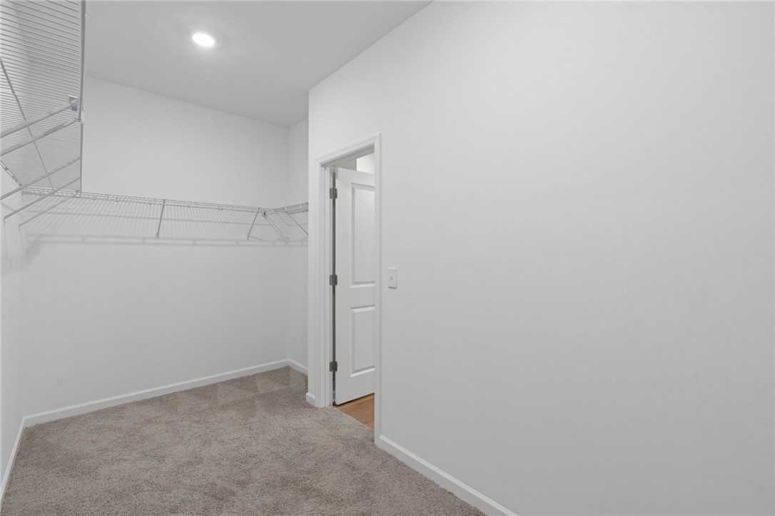 Spacious walk-in closet featuring wire shelving, white walls, and carpeted floor in Davidson Homes The Luna B, Opelika, Alabama