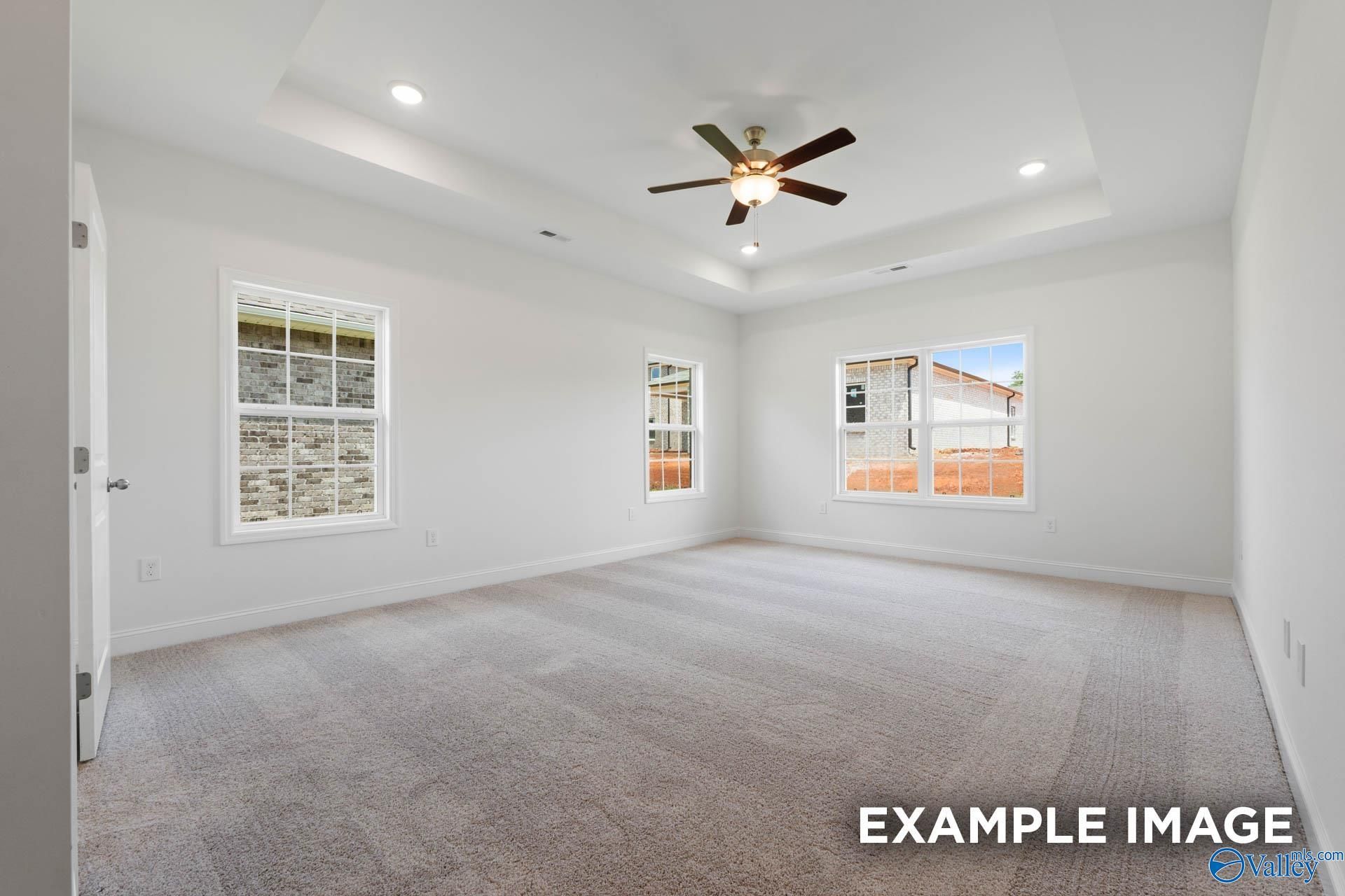 Spacious empty bedroom featuring ceiling fan, recessed lights, and large windows in Davidson Homes The Oxford, Huntsville, Alabama