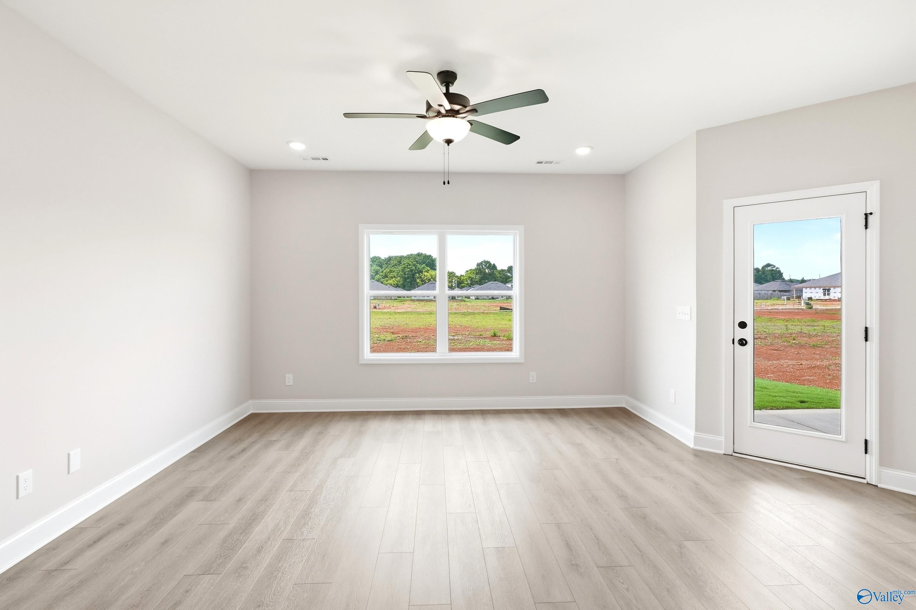 Bright, spacious living area with wood-look flooring and ceiling fan in The Daphne floor plan in Lynn Meadows, Alabama.