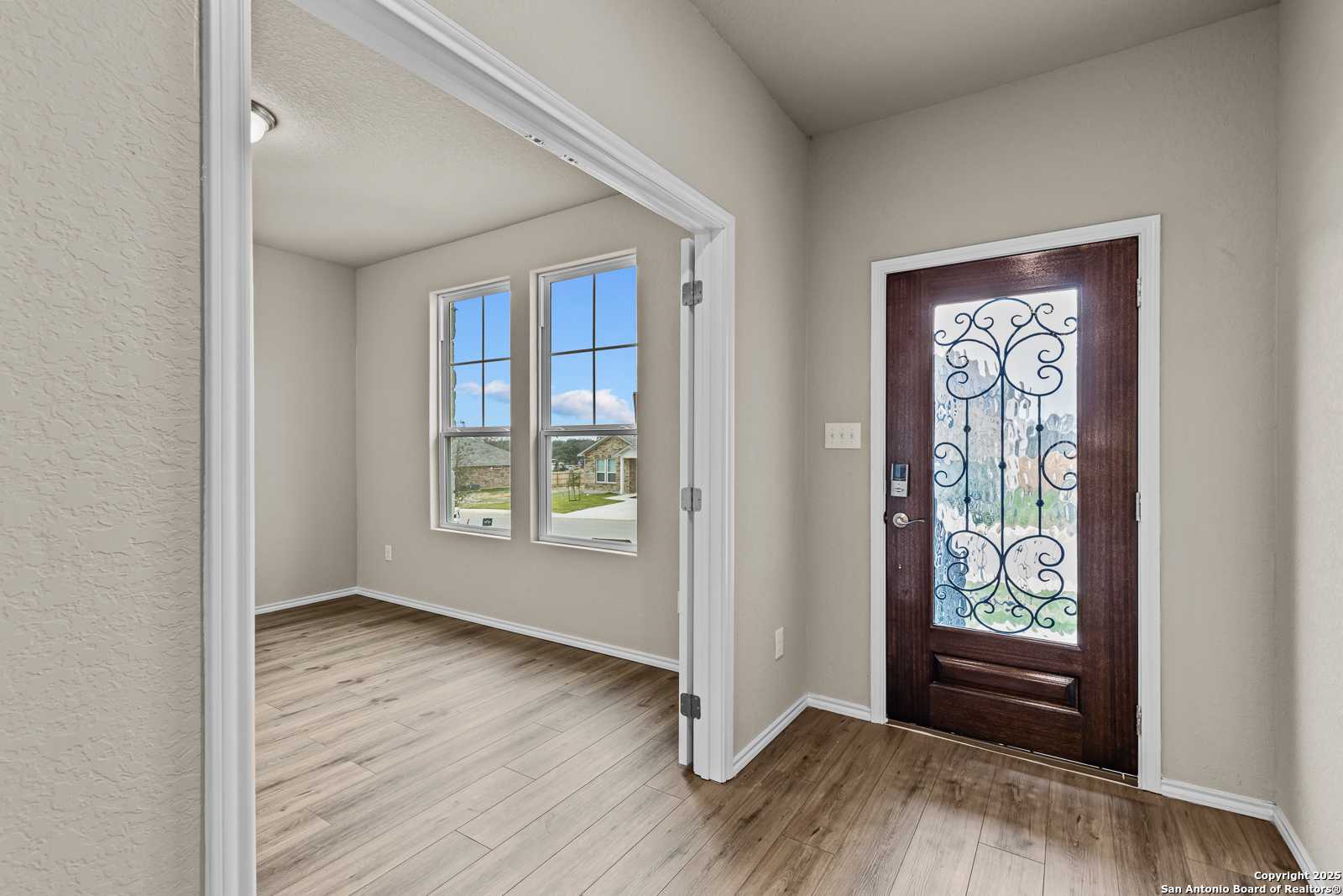Elegant foyer with wrought iron front door, hardwood floors, and large windows in Davidson Homes The Douglas F, San Antonio