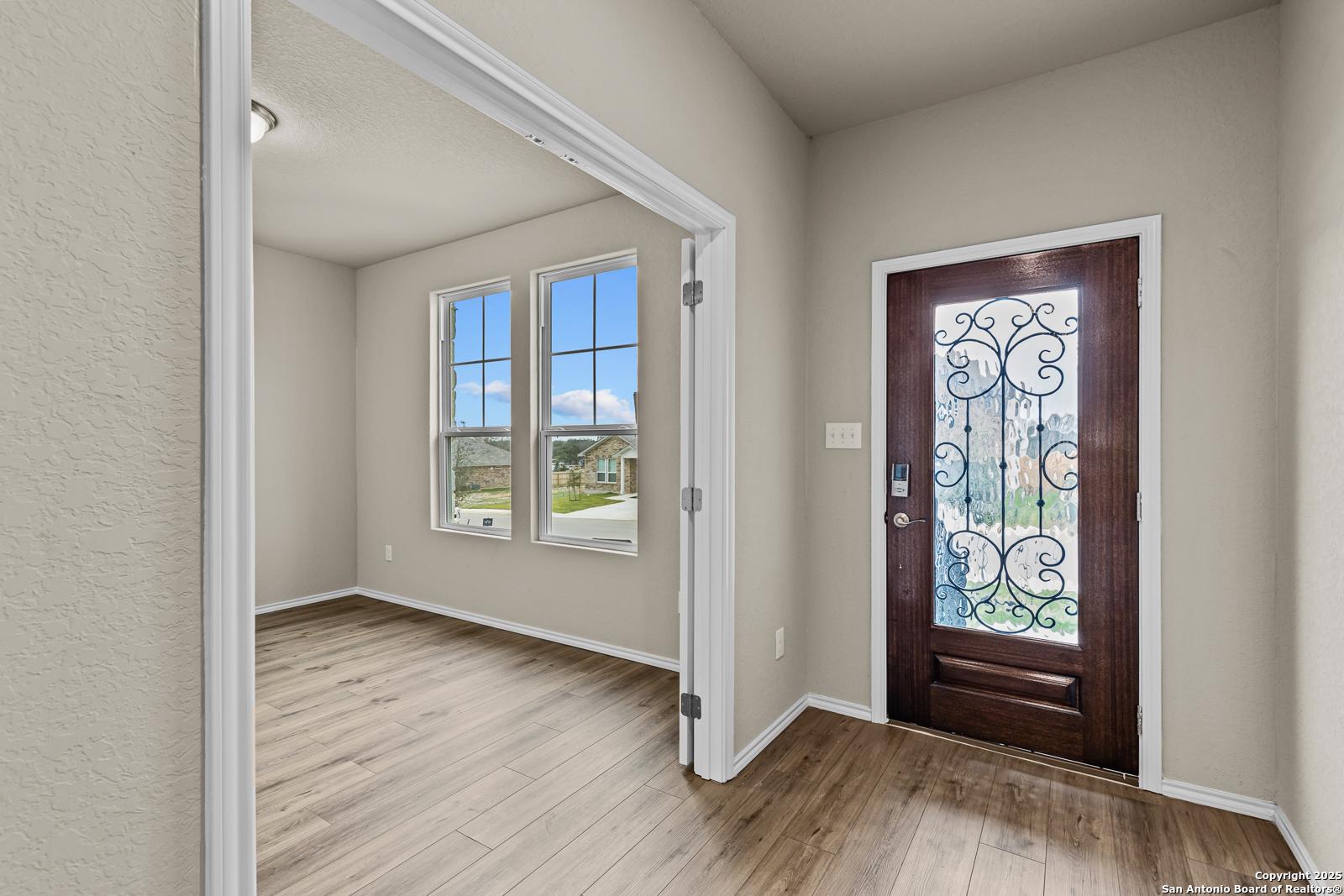 Elegant foyer with wrought iron front door, hardwood floors, and large windows in Davidson Homes The Douglas F, San Antonio