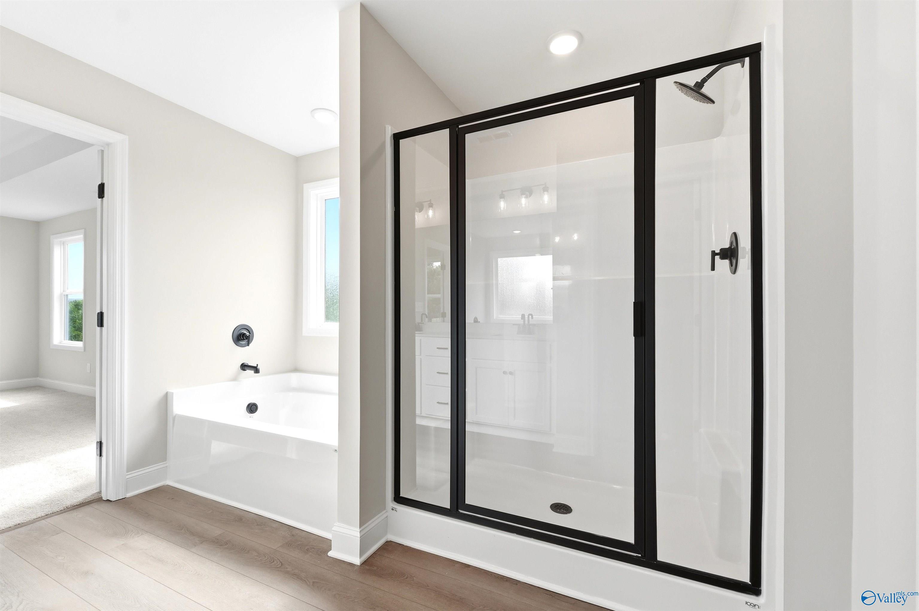 Modern primary bathroom with walk-in glass shower and soaking tub in The Chelsea D floor plan at Berry Cove, New Market.