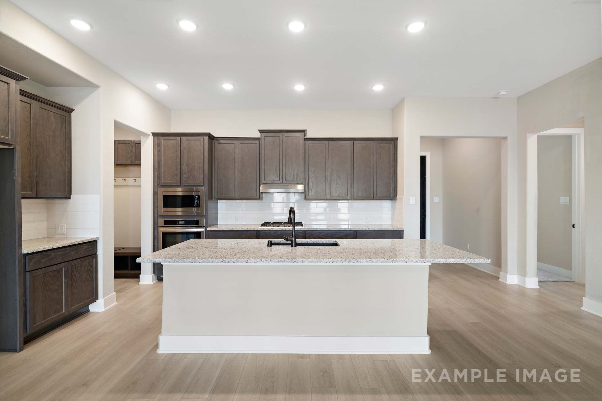 Gourmet kitchen in The Elizabeth by Davidson Homes featuring large granite island, dark wood cabinets, and open floor plan