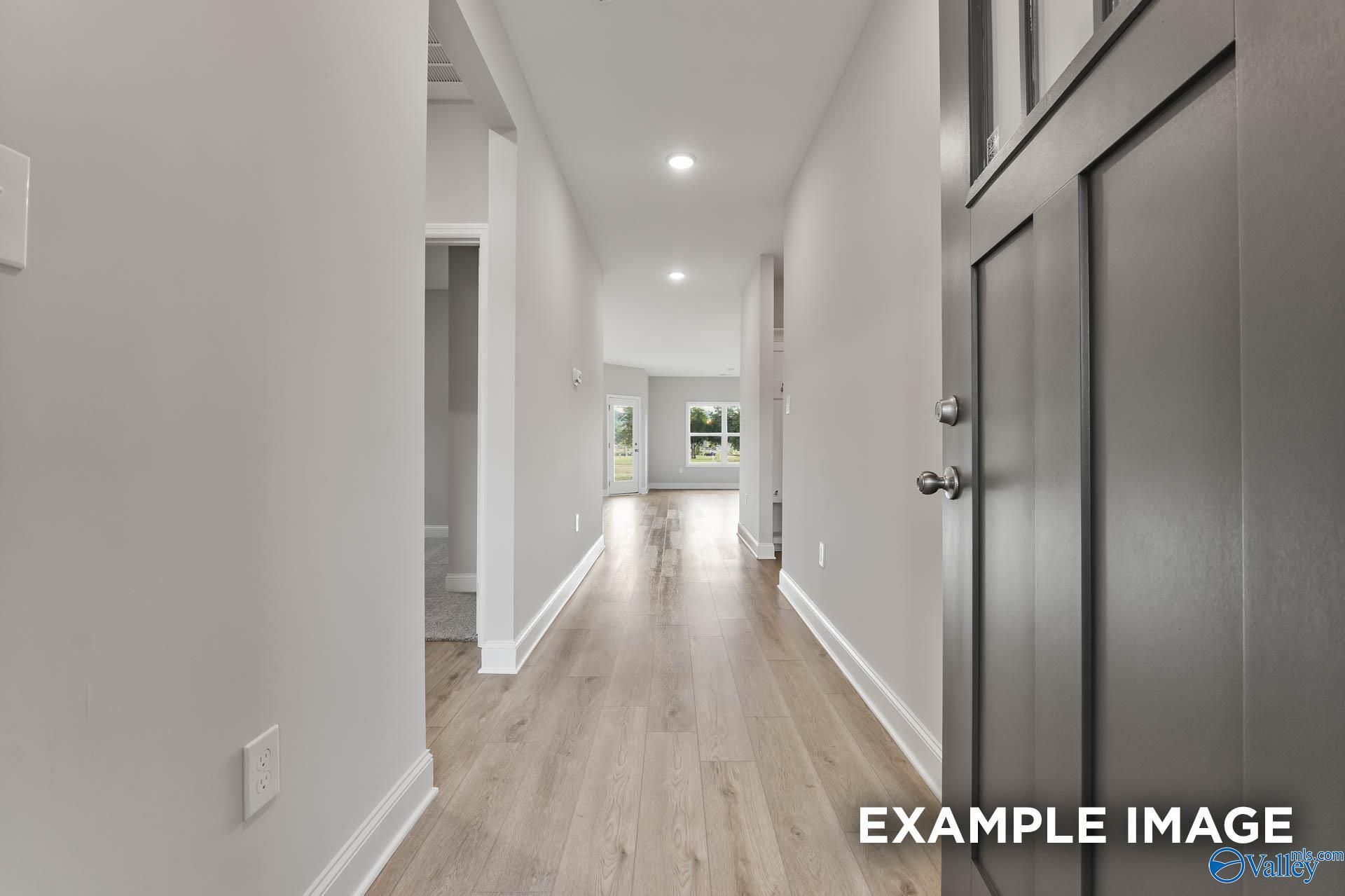 Inviting hallway with light gray walls, oak hardwood floors, and recessed lights in Davidson Homes The Franklin C, Toney, Alabama