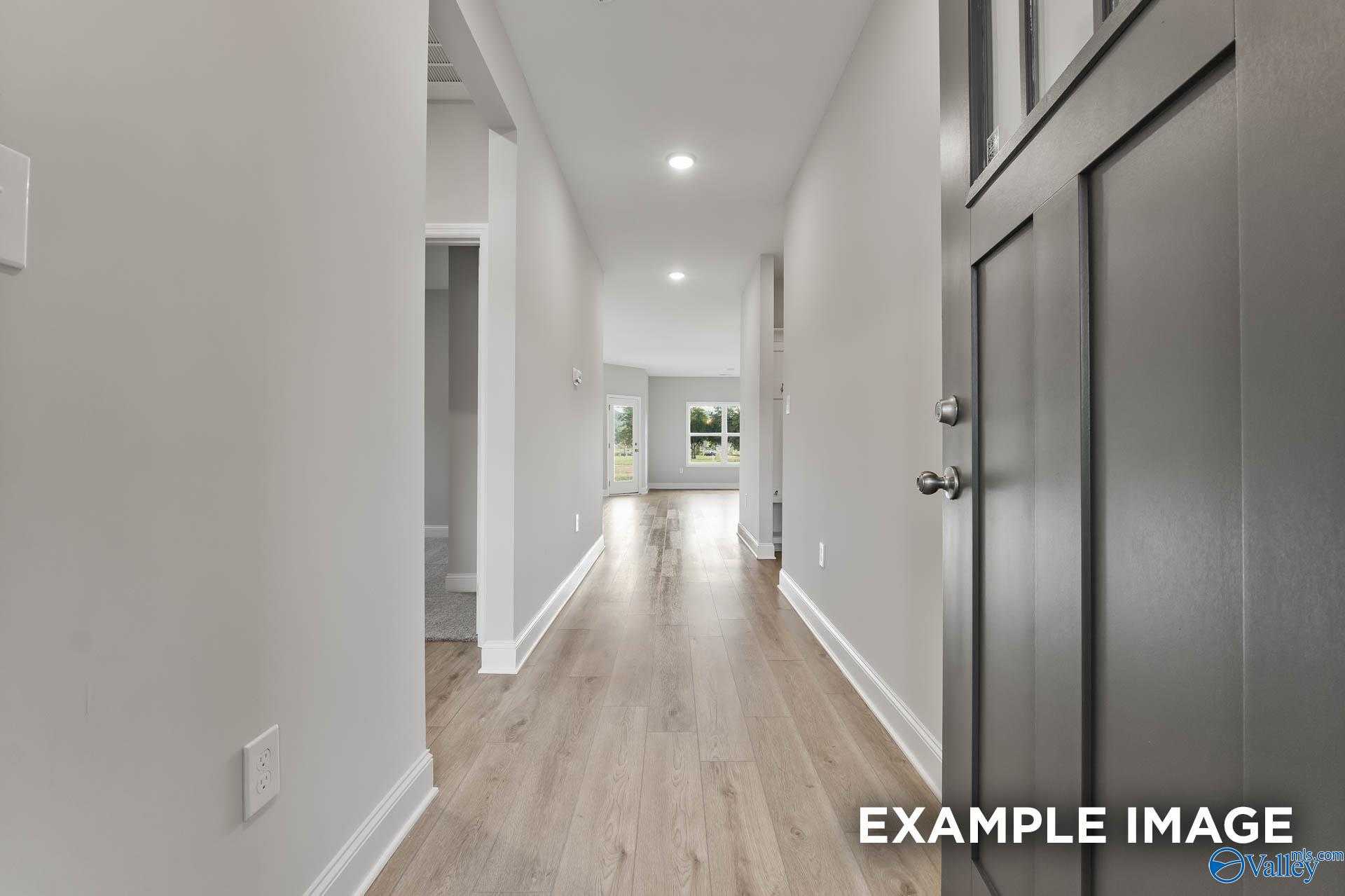 Bright hallway with oak hardwood floors, recessed lighting, and front door in Davidson Homes The Franklin C, Athens Alabama