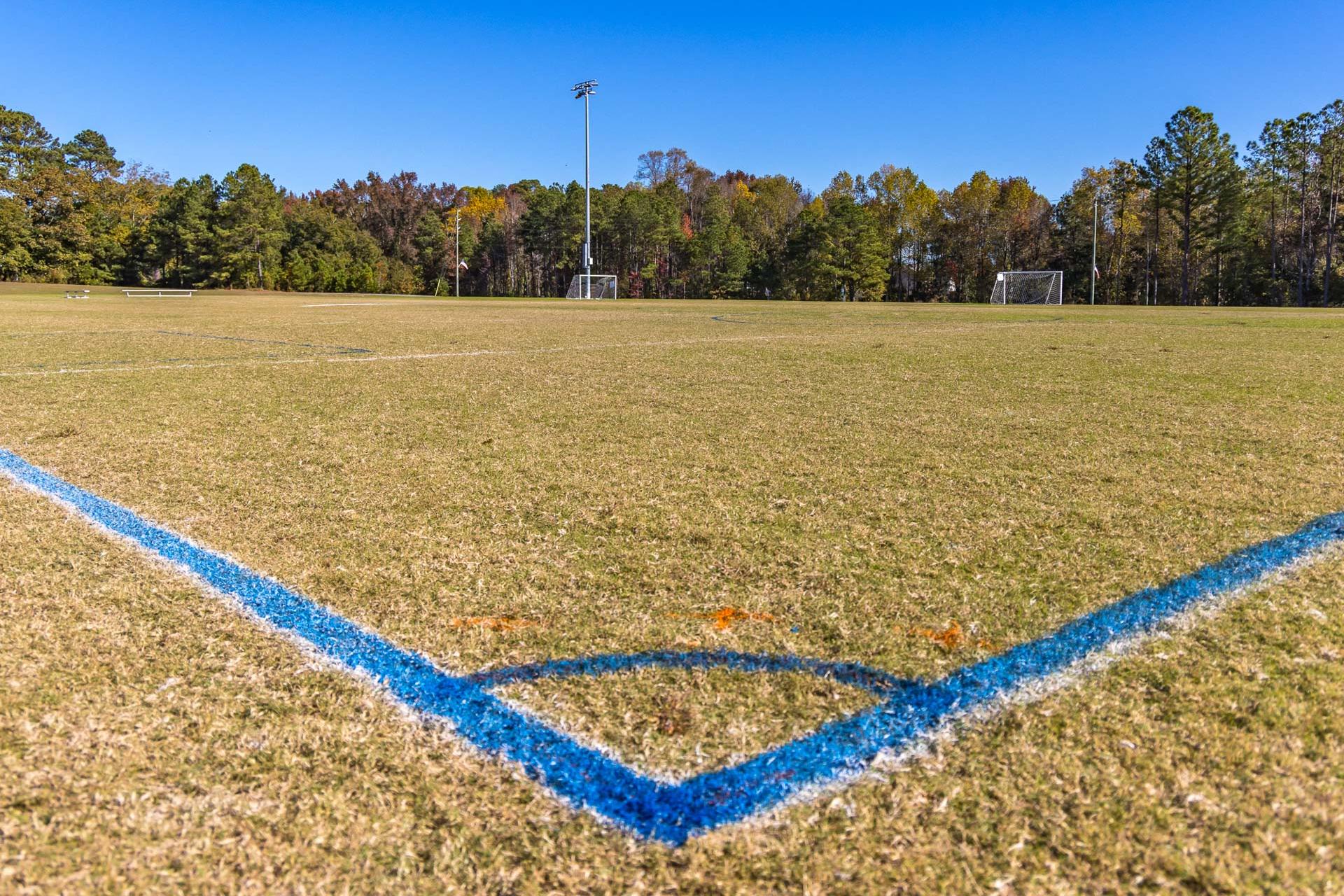 Expansive soccer field with goals and floodlights at Highland Forest in Fuquay-Varina NC amid autumn trees