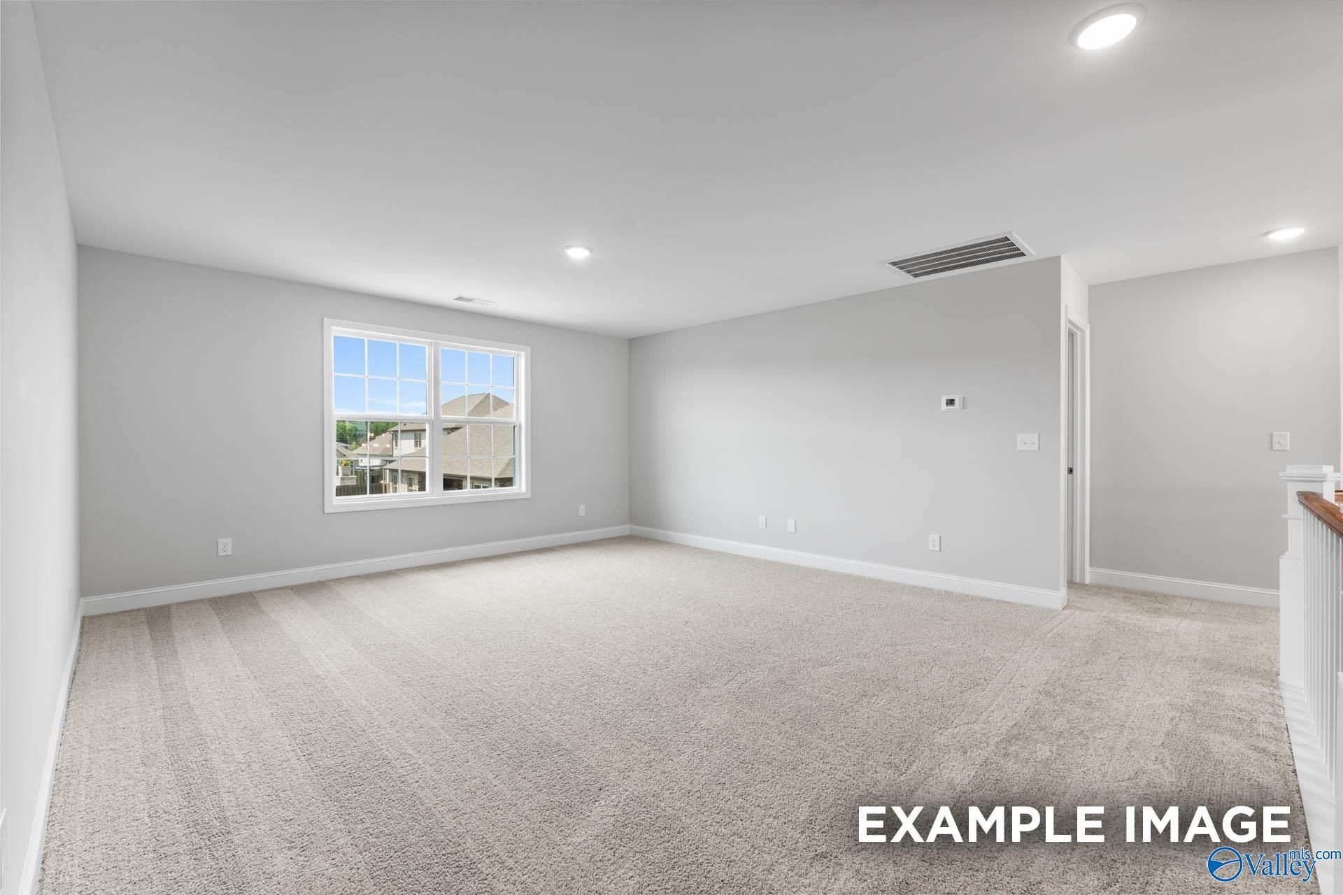 Spacious empty bedroom with gray walls, beige carpet, large window overlooking suburban neighborhood in 5-bed Madison D home, Madison, Alabama