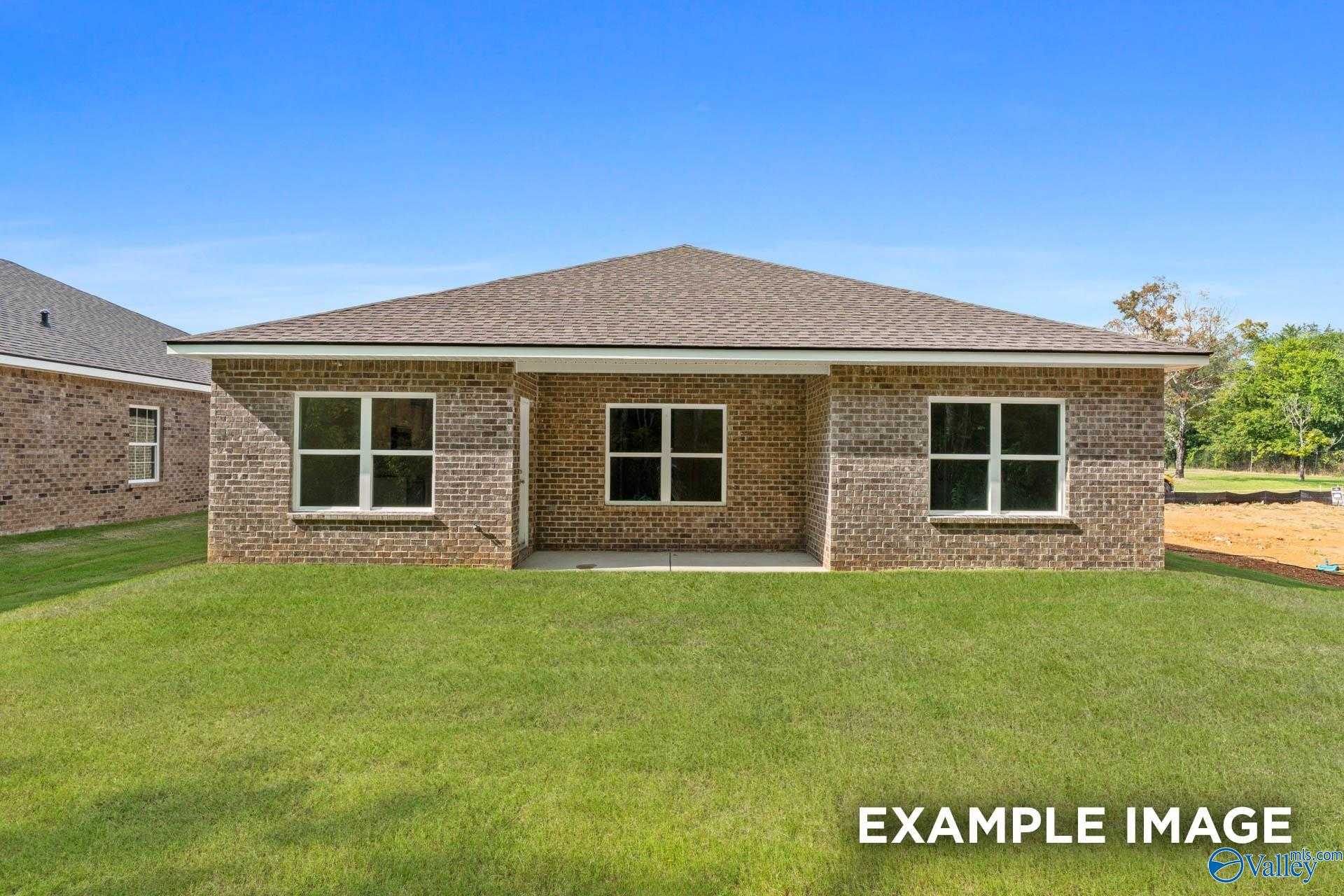 Front view of single-story brick home with gabled roof, triple windows, and covered entry on lush green lawn in Ramsay Cove, Owens Cross Roads, Alabama