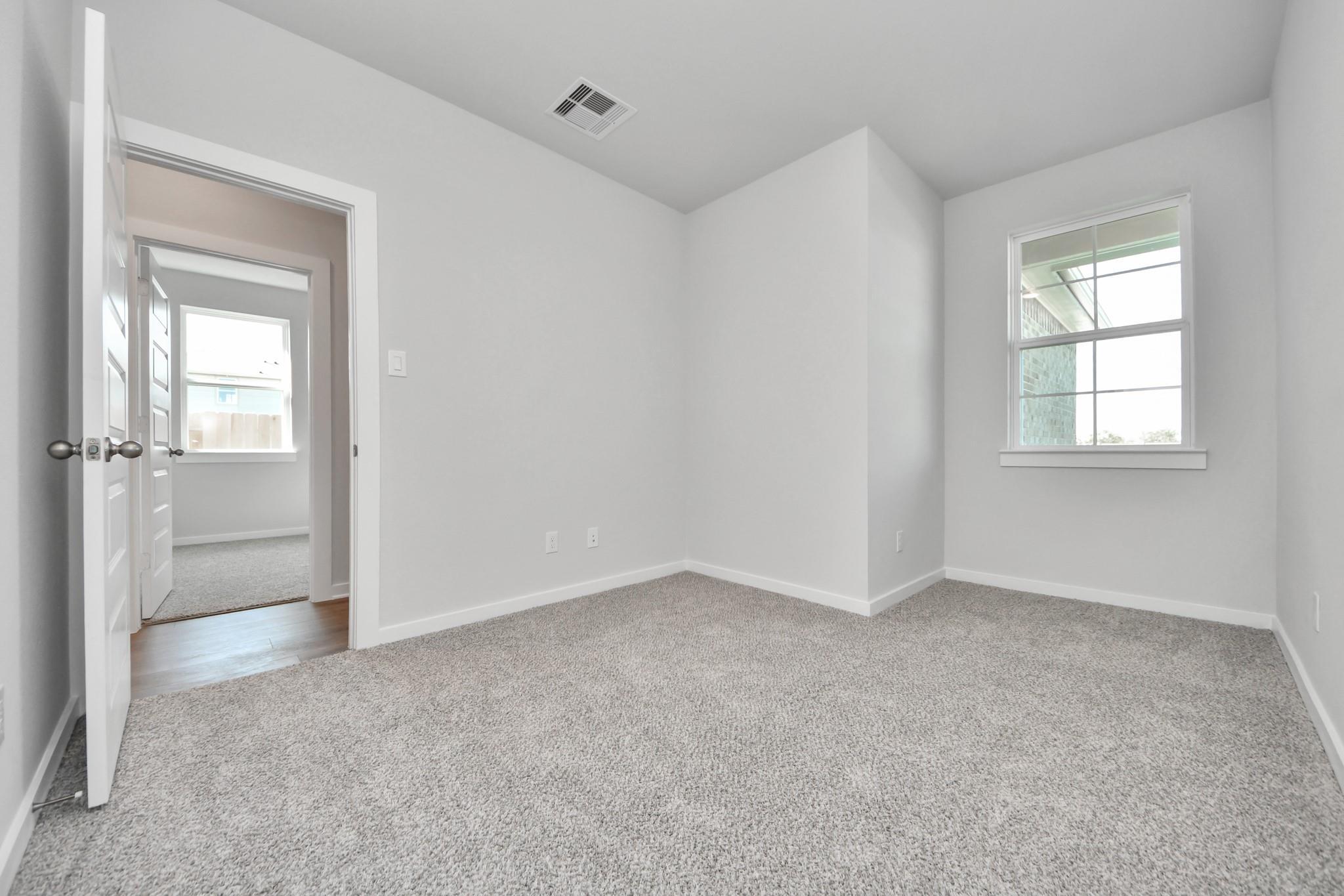 Bright, carpeted spare bedroom in The Colorado G floor plan at Emberly, a Davidson Homes community in Beasley, Texas.