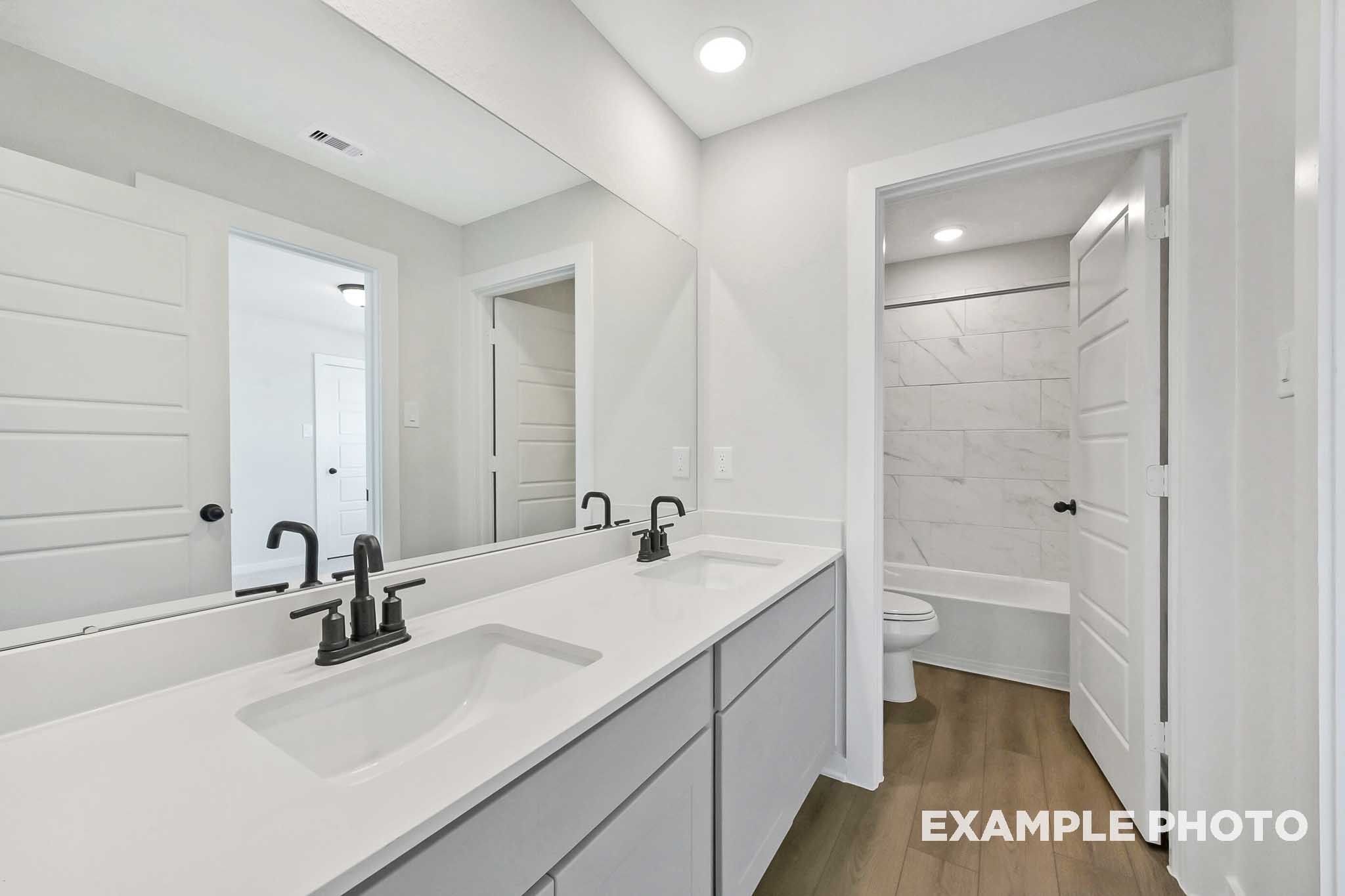 Elegant master bathroom in The Sequoia featuring double white vanity, soaking tub, and tiled walk-in shower
