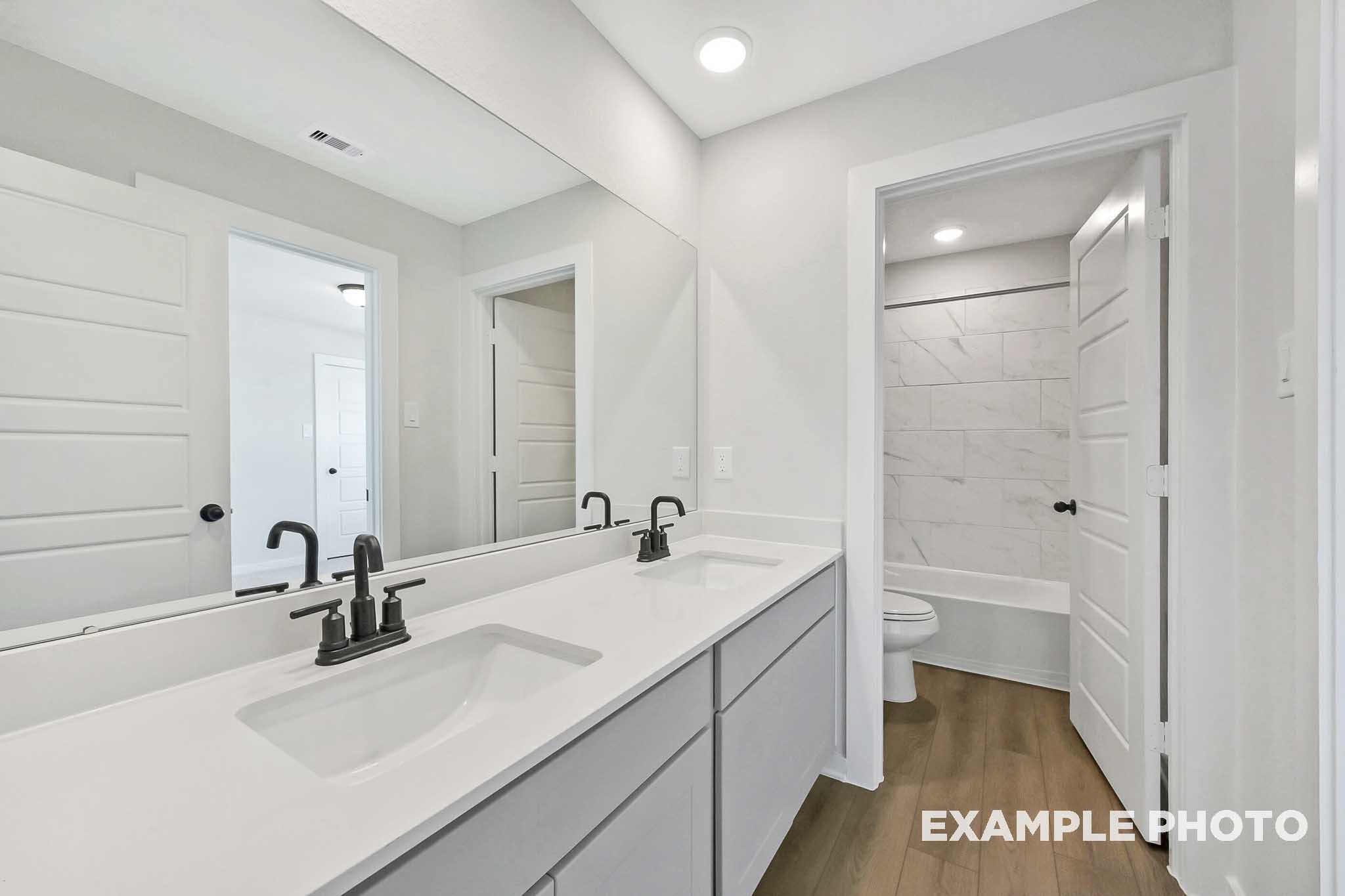 Elegant master bathroom in The Sequoia featuring double white vanity, soaking tub, and tiled walk-in shower