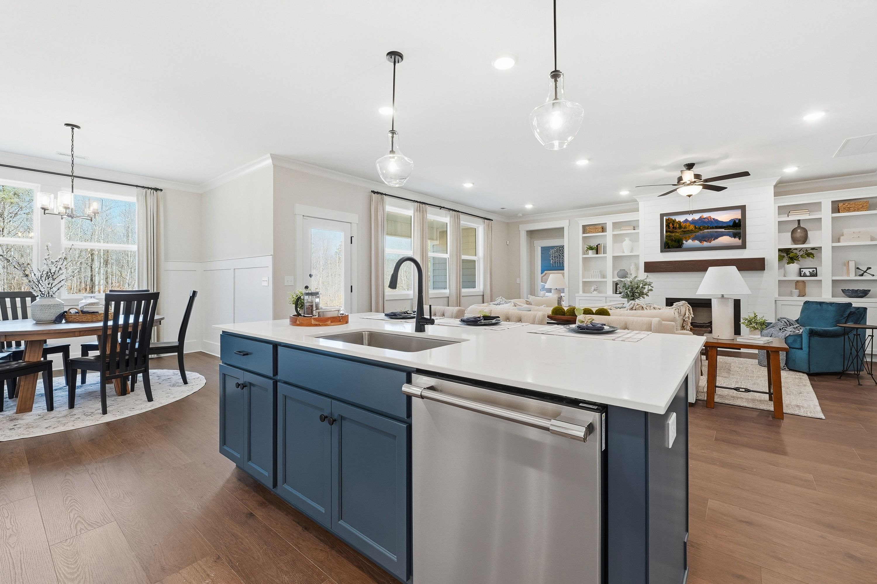 Open-concept kitchen and living area at Noble Ridge in Cullman Alabama with navy island, hardwood floors, and fireplace