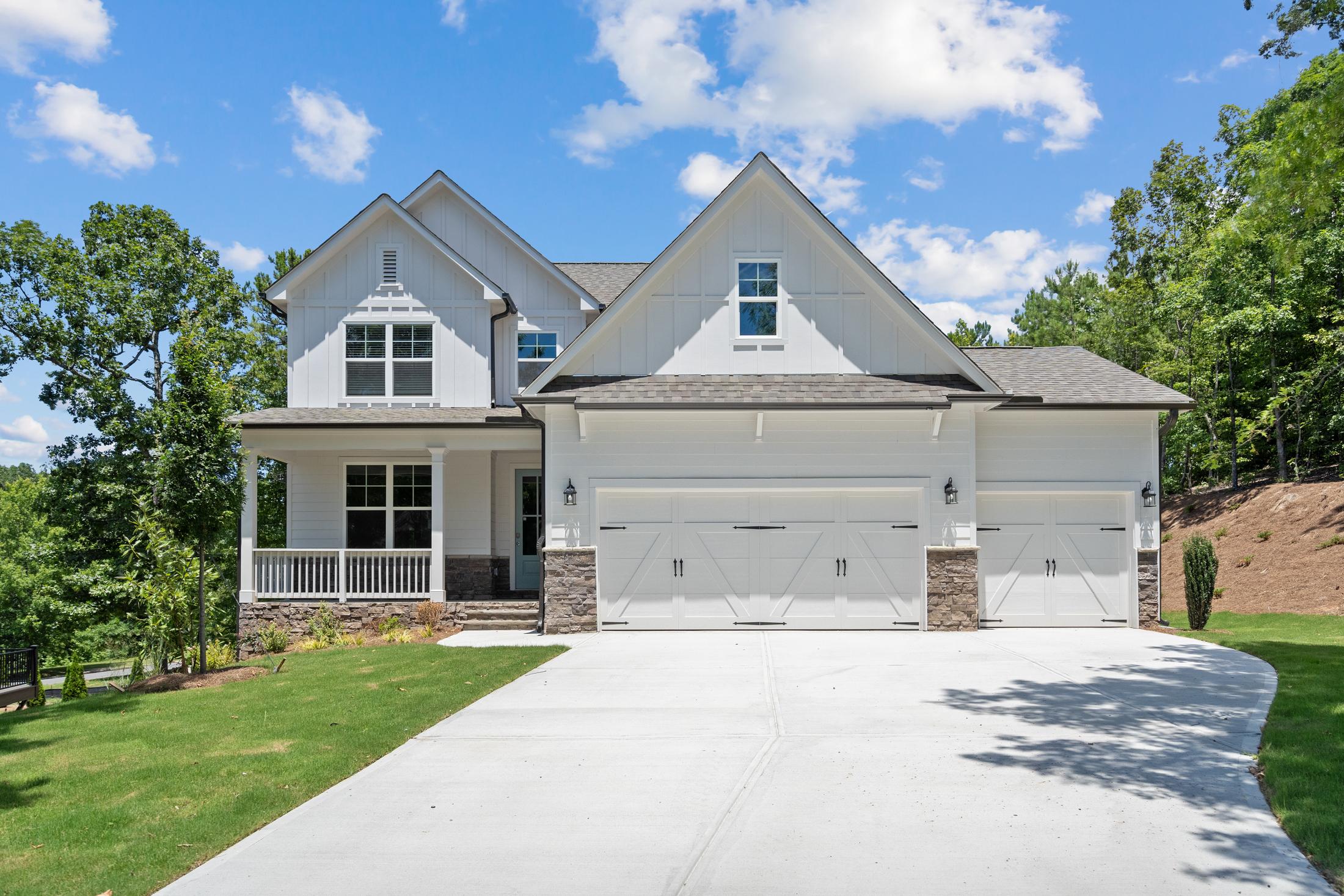 Modern farmhouse home exterior at Mountainbrook in Cartersville GA with white siding, covered porch, two-car garage and lush landscaping
