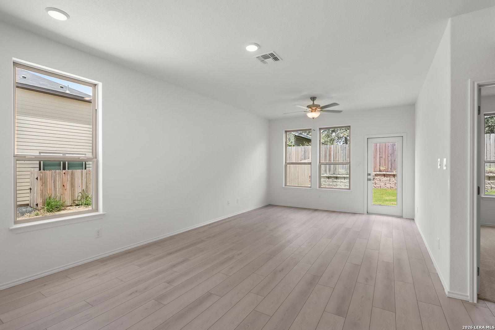 Bright living area with light wood-look floors in The Gillian C floor plan at Meadows at Oak Creek, San Antonio, Texas.