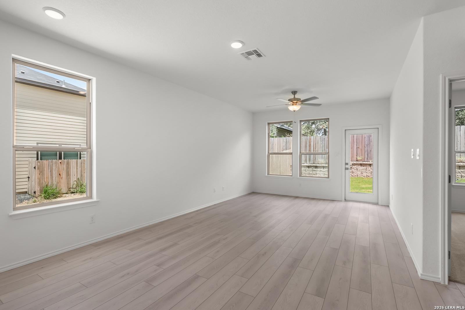 Bright living area with light wood-look floors in The Gillian C floor plan at Meadows at Oak Creek, San Antonio, Texas.