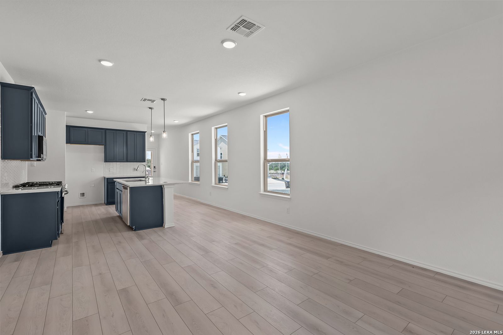 Open-concept kitchen with navy cabinets and island in The Gillian C floor plan at Meadows at Oak Creek, San Antonio.
