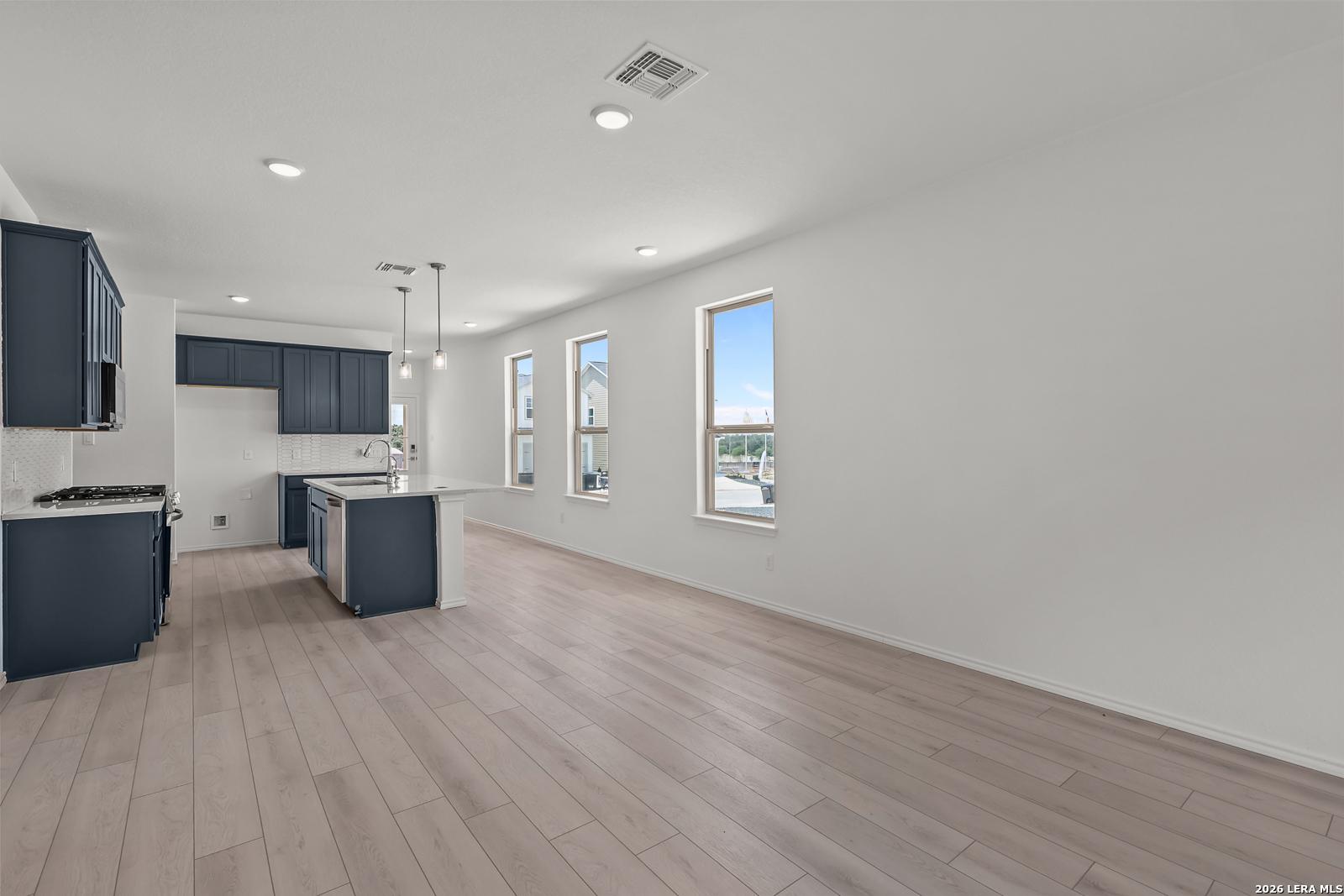 Open-concept kitchen with navy cabinets and island in The Gillian C floor plan at Meadows at Oak Creek, San Antonio.