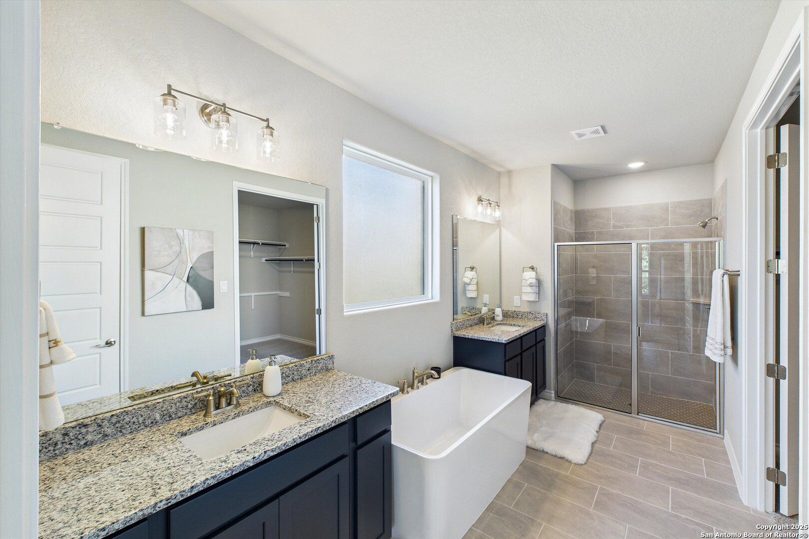 Elegant master bathroom featuring freestanding tub, double vanity with granite counters, walk-in shower in Davidson Homes The Jennings H, San Antonio