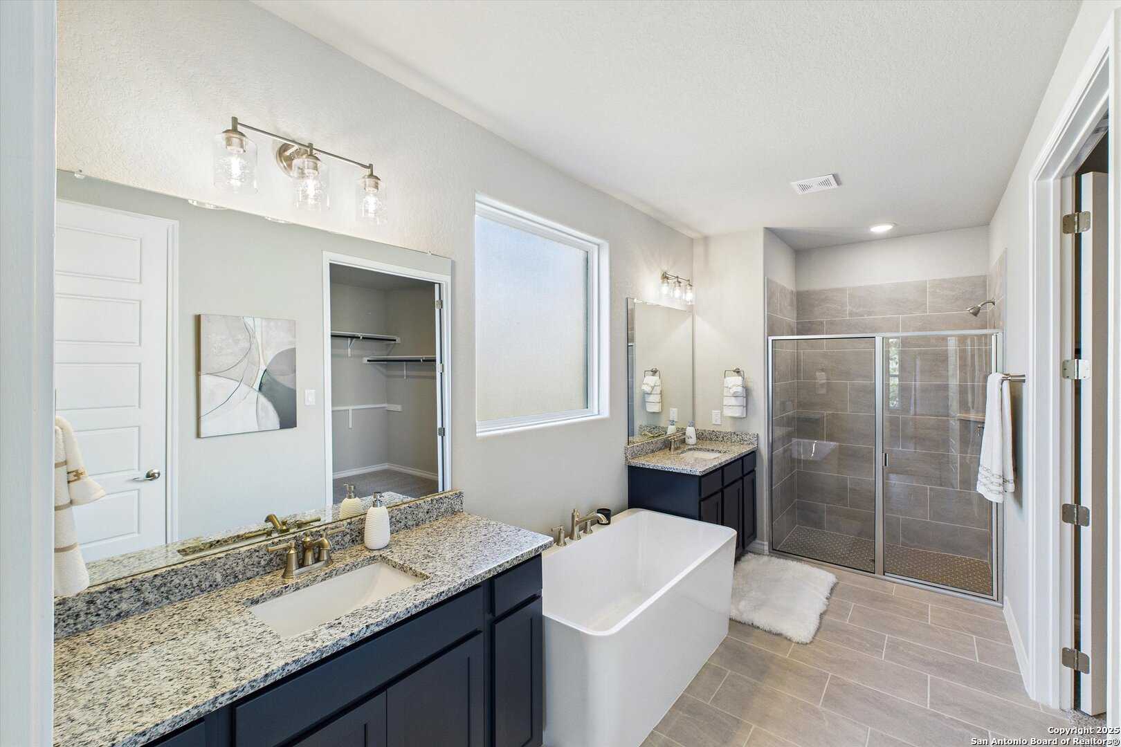 Elegant master bathroom featuring freestanding tub, double vanity with granite counters, walk-in shower in Davidson Homes The Jennings H, San Antonio