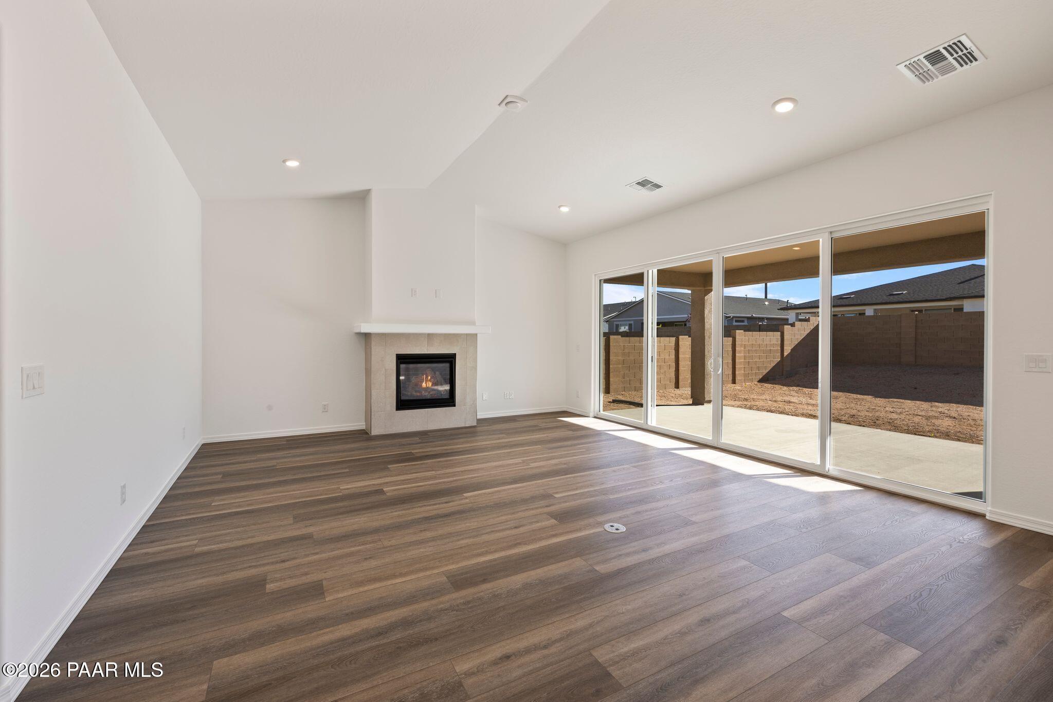 Open great room featuring gas fireplace, luxury vinyl plank floors, and sliding doors to desert patio in Davidson Homes Sunrise II A, Prescott AZ