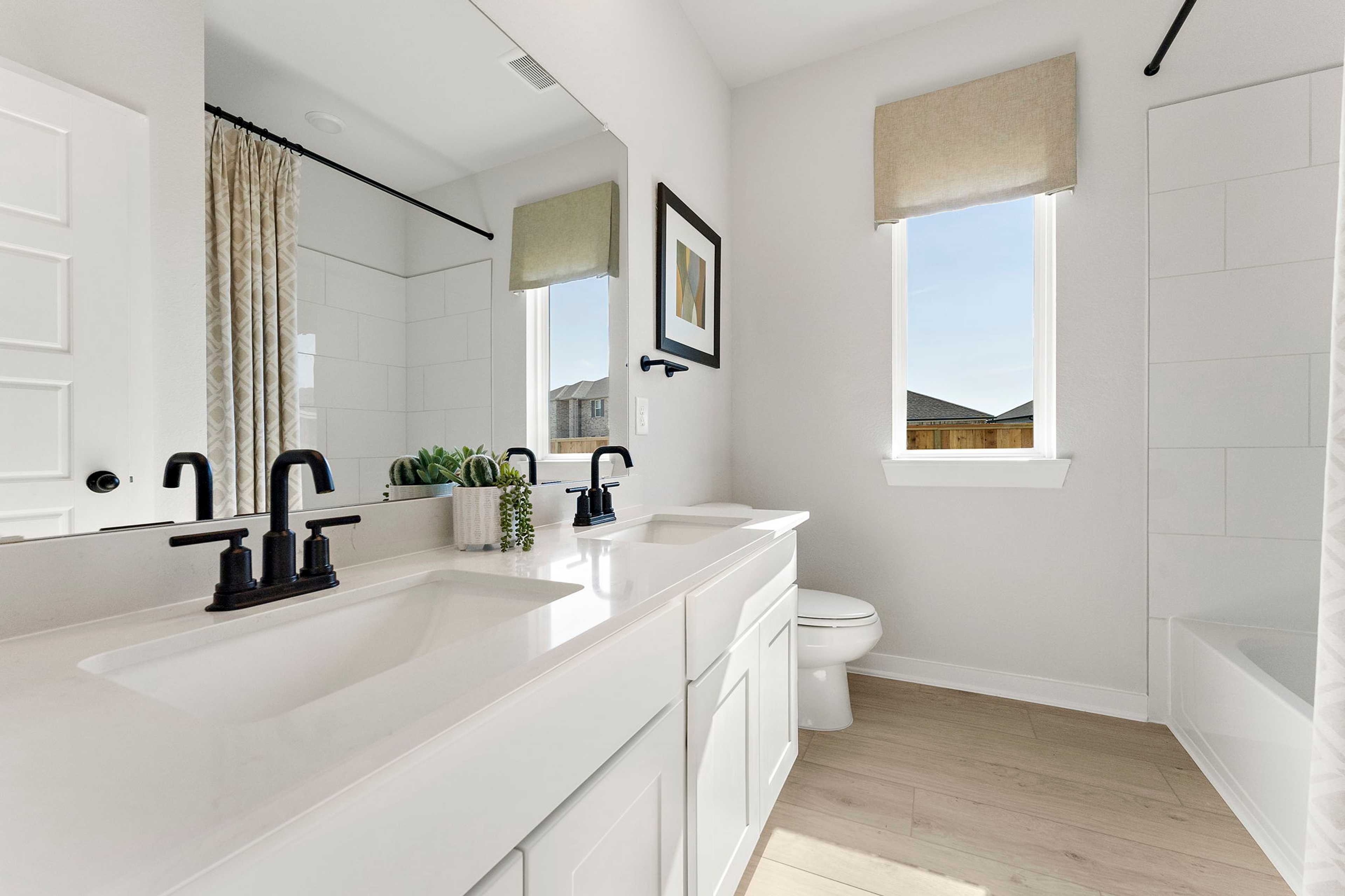 Spacious bathroom at Sundance Cove in Crosby Texas with double white vanity black faucets freestanding tub and natural light