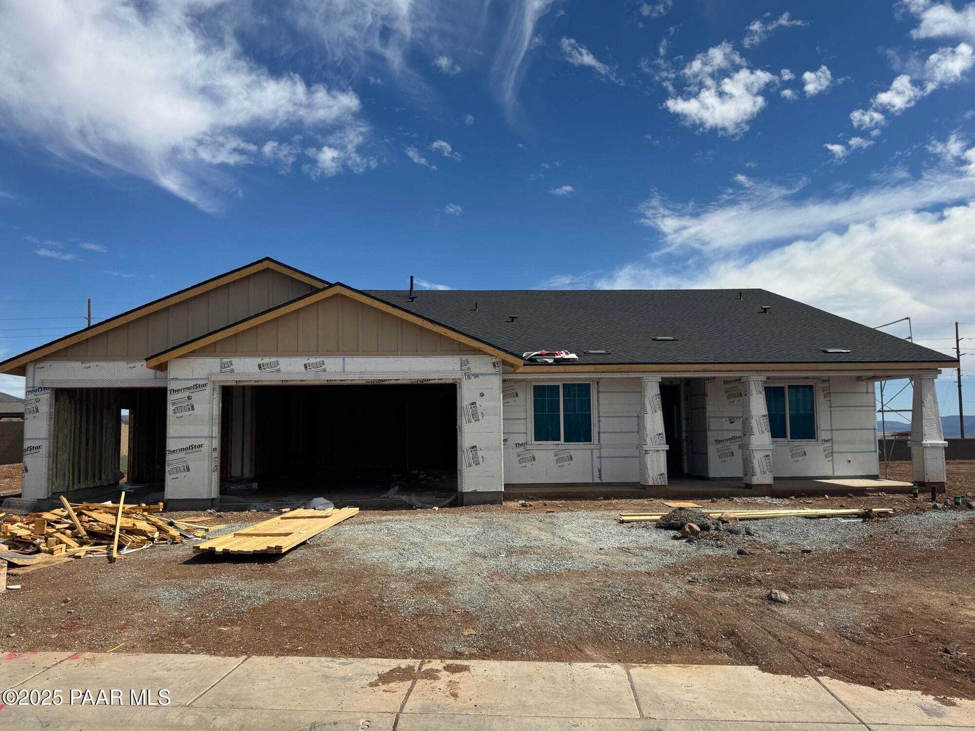 Partially constructed 1-story home with open 4-car garage, beige siding, and dark roof in Morningstar, Prescott Valley, Arizona - Evermore Homes The Sunrise A