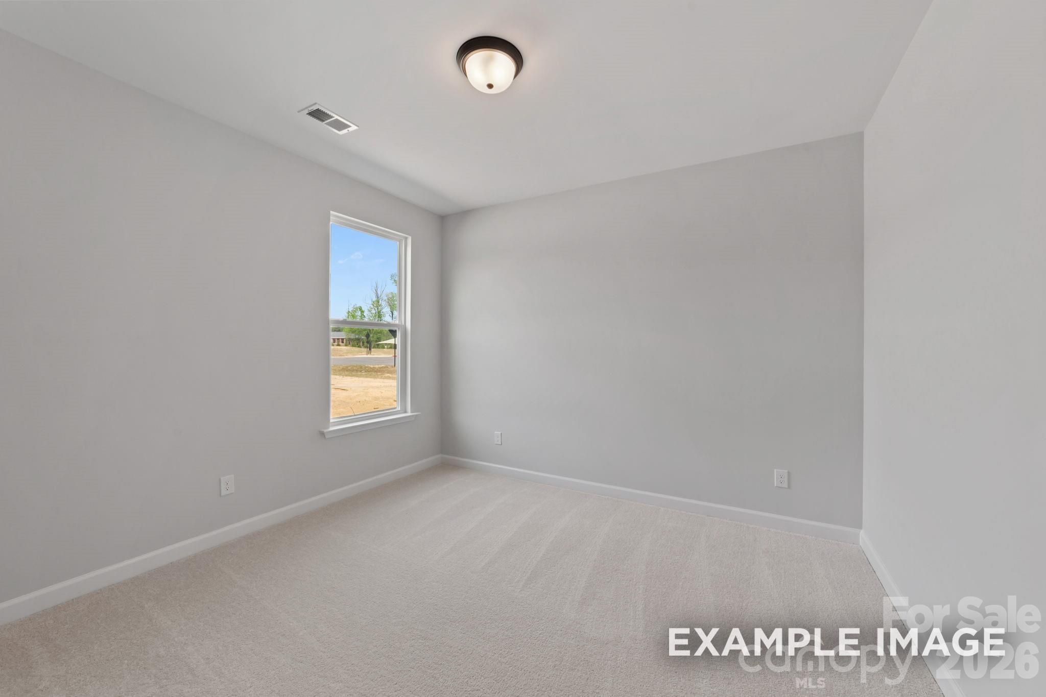 Bright, spacious bedroom with neutral carpet in The Magnolia B floor plan at Windgate in Mooresville, North Carolina.