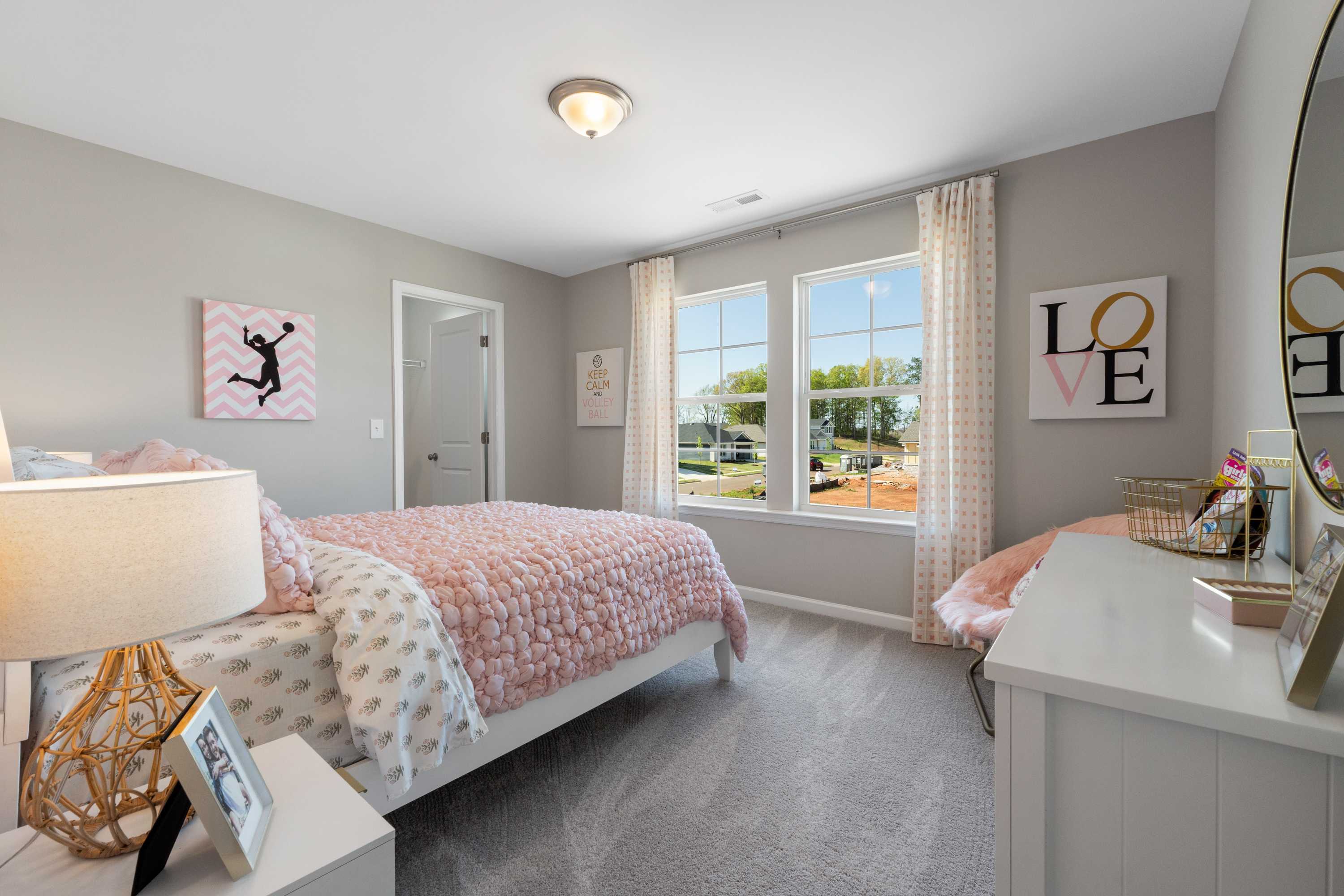 Cozy girl's bedroom at Evergreen Mill in Madison AL with pink quilted bed vanity mirror and large windows