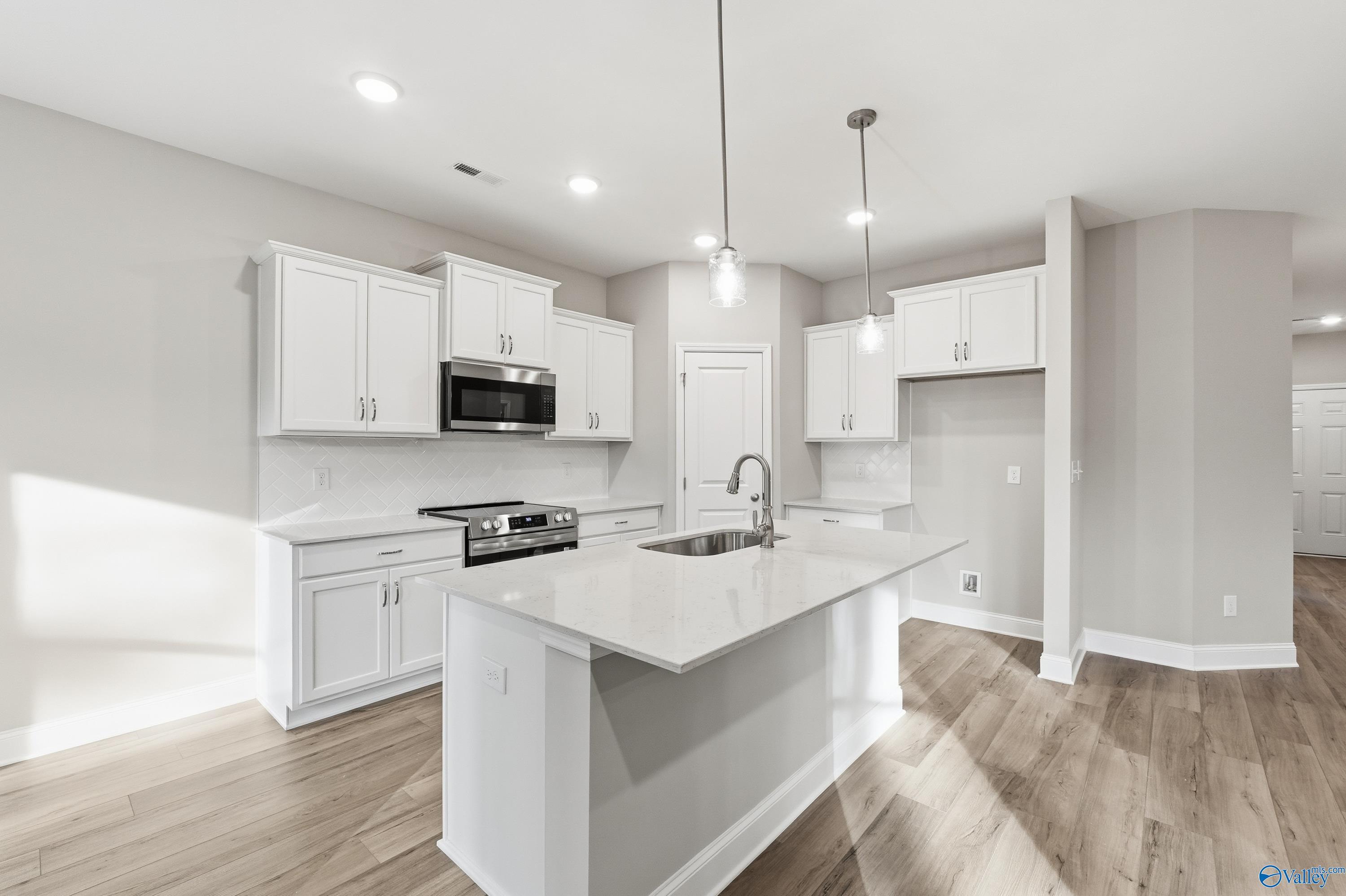 Modern white kitchen with island, quartz countertops, and stainless appliances in The Asheville floor plan, Arab, AL.