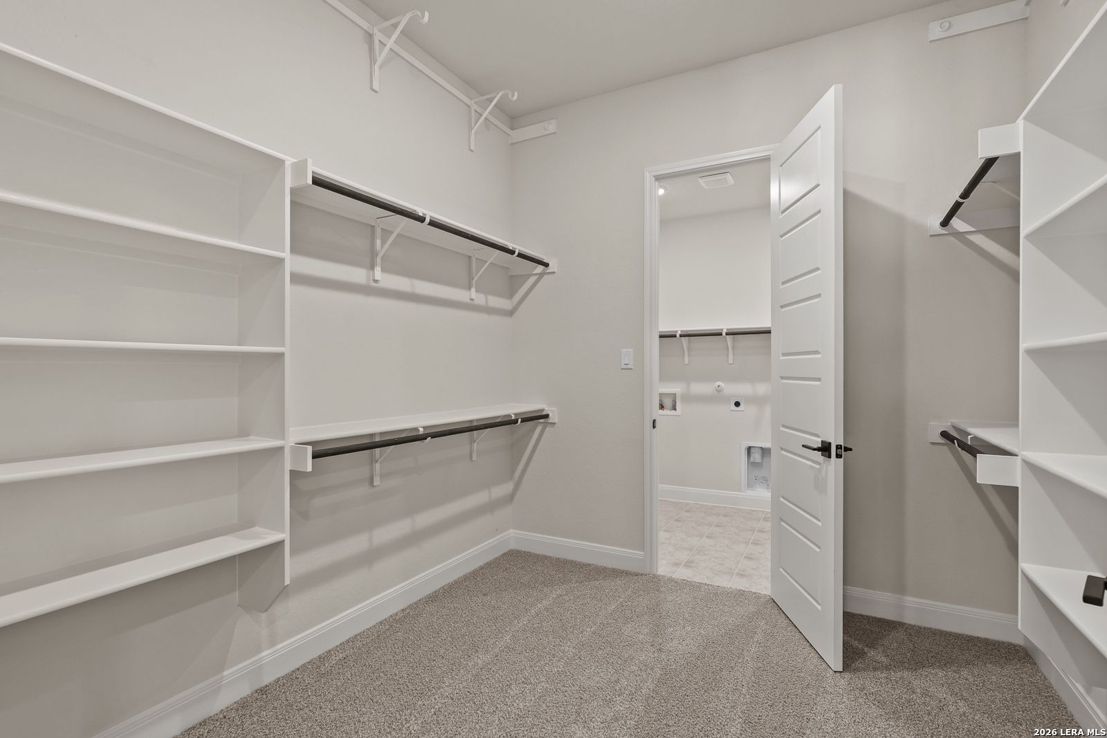 Walk-in closet with built-in shelving connecting to the laundry room in The Summerlin B home, Potranco Oaks, Castroville.