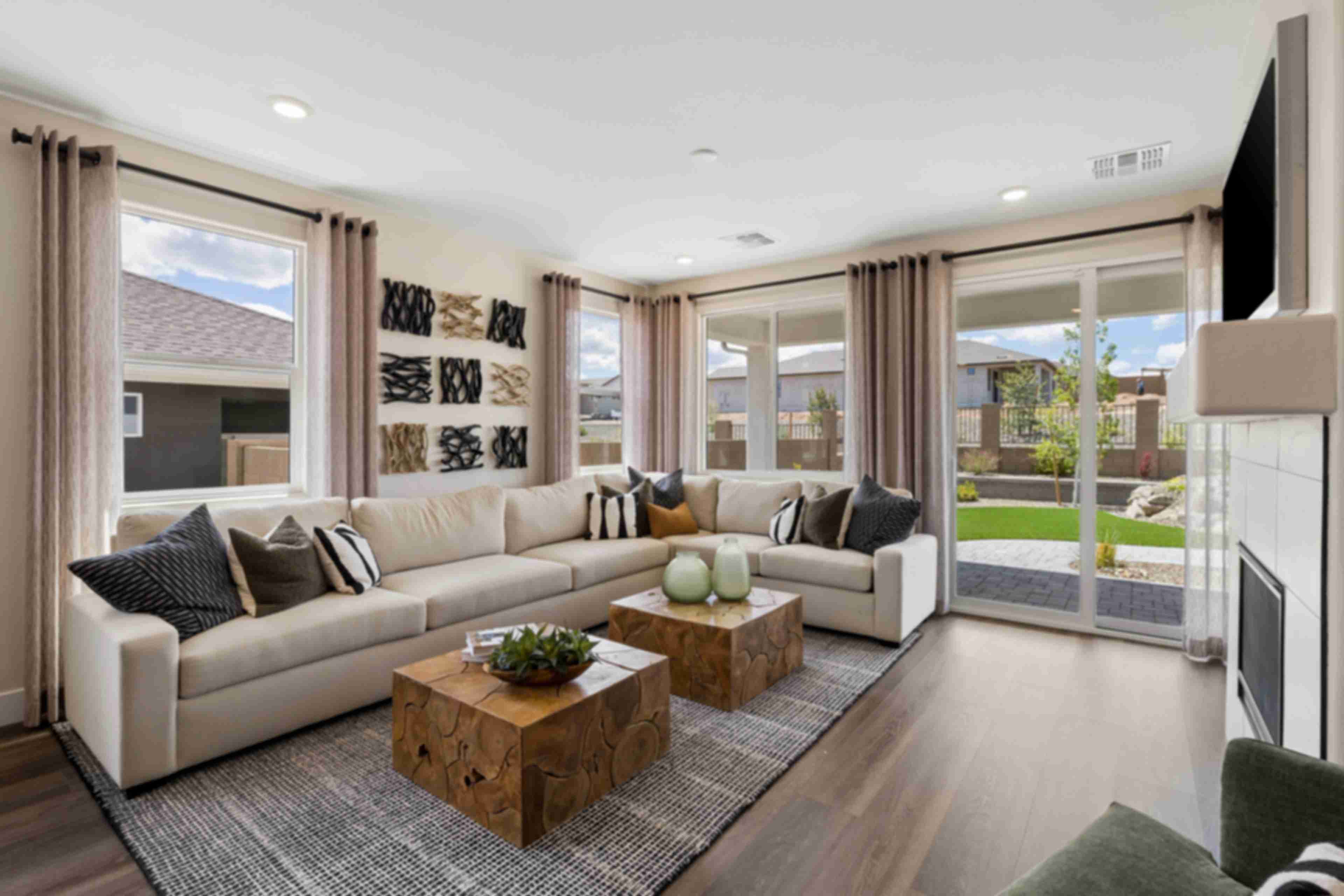 Spacious living room in South Ranch Western Collection, Prescott AZ with white sectional sofa, wood coffee table, fireplace, and large sliding doors