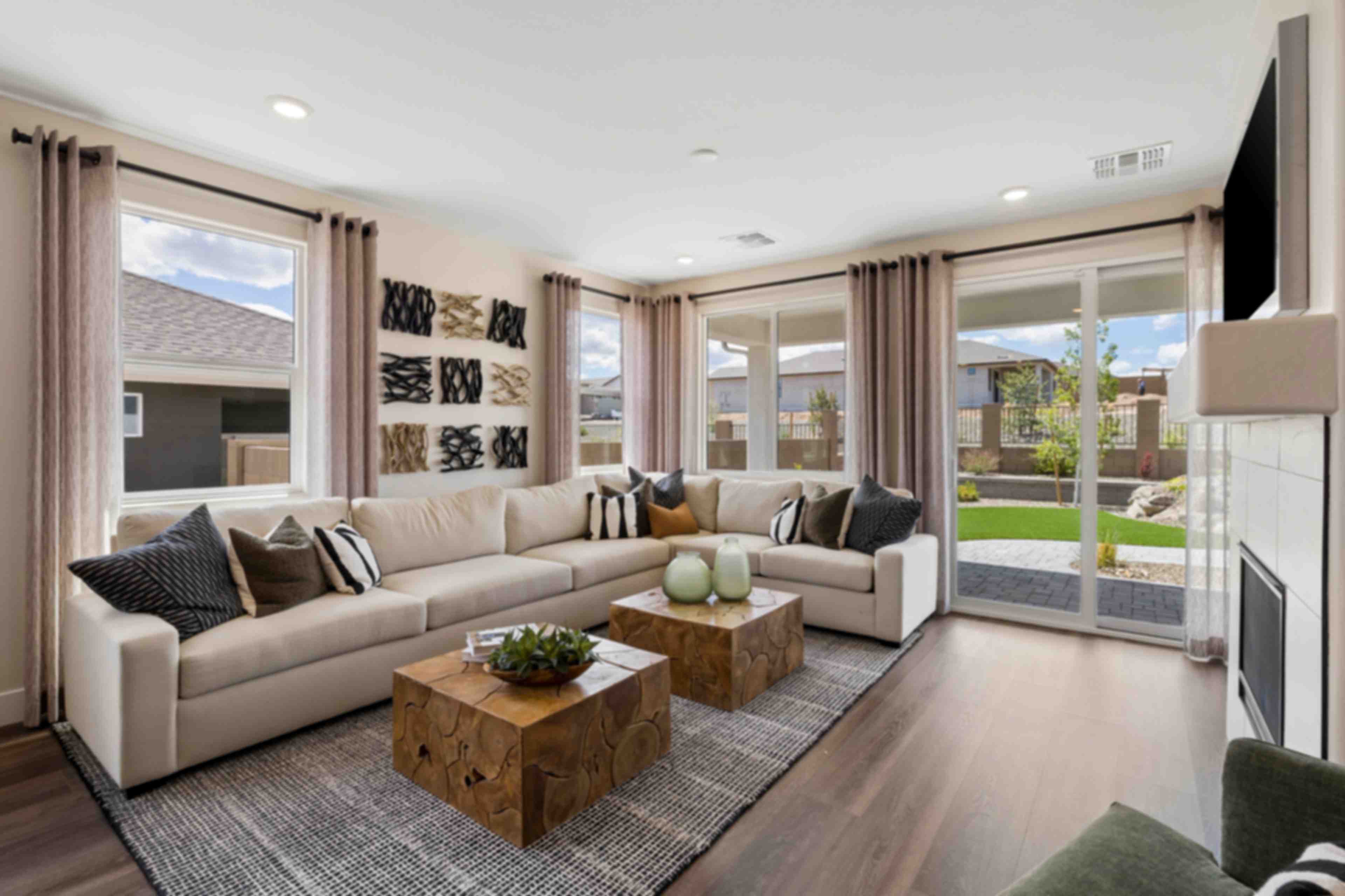 Spacious living room in South Ranch Western Collection, Prescott AZ with white sectional sofa, wood coffee table, fireplace, and large sliding doors