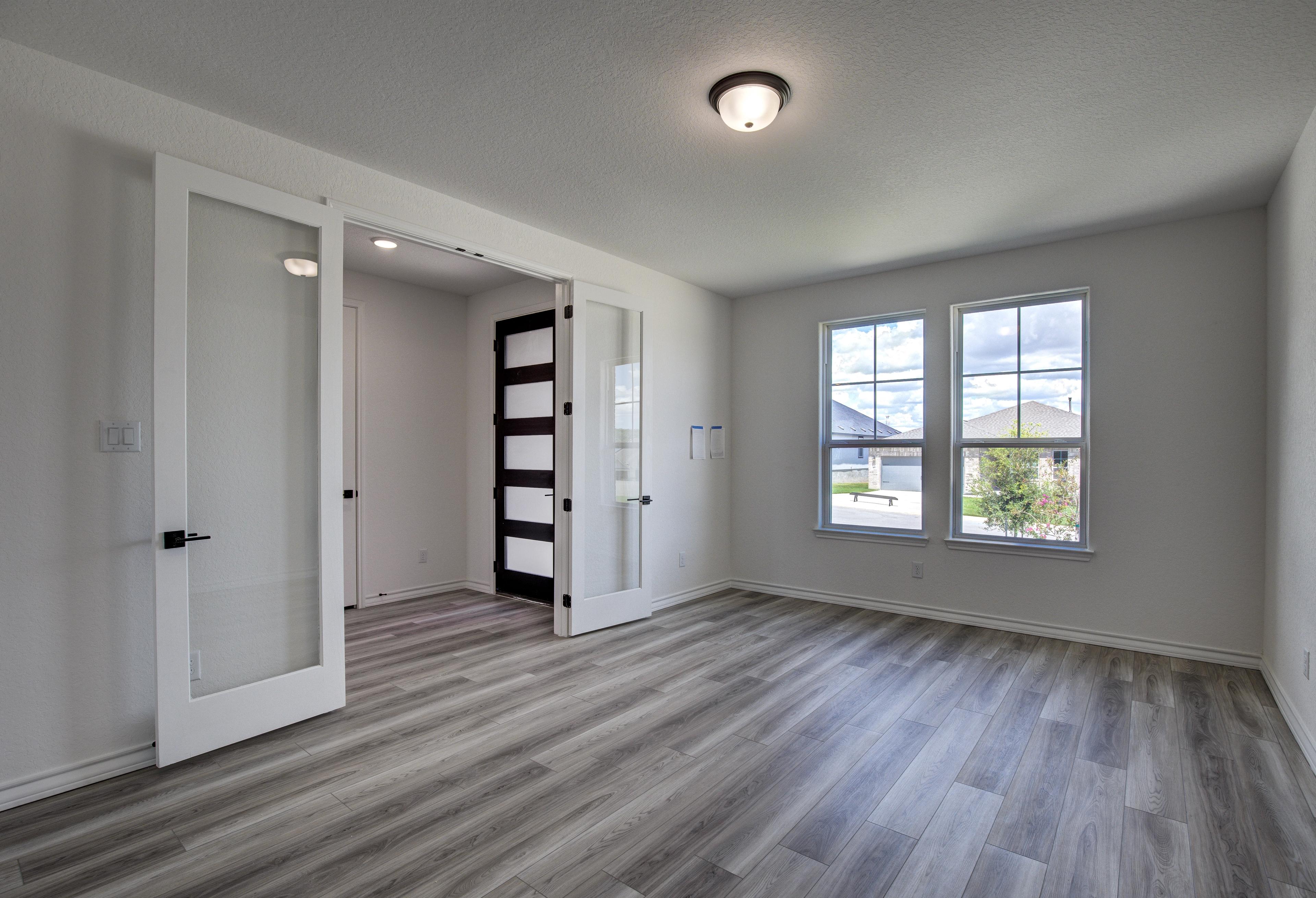 Spacious The Lanier home interior with frosted glass doors, large windows, light gray walls, and laminate flooring