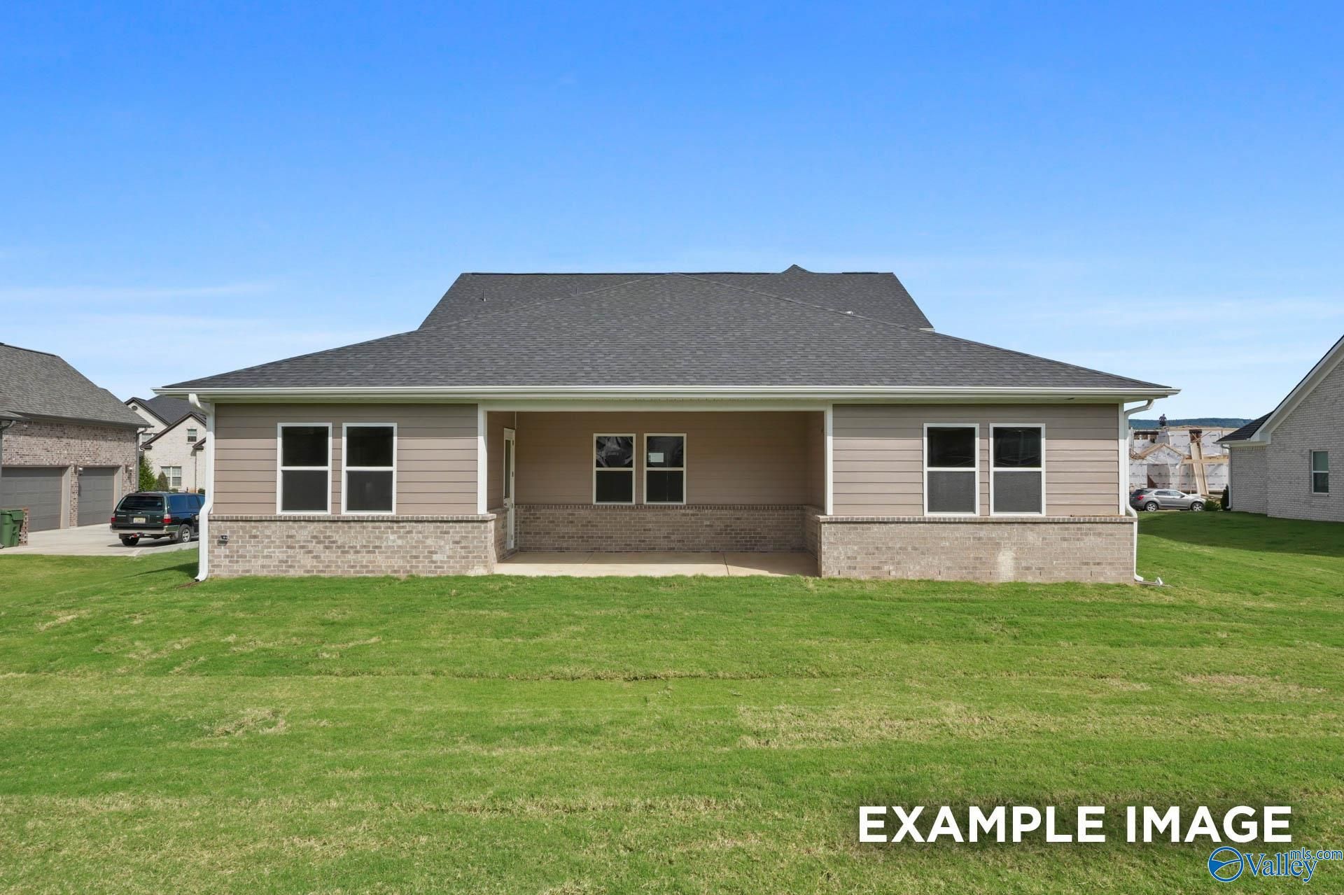 Two-story Haven E home with beige siding, brick base, covered porch, and green lawn in The Meadows at Hampton Cove, Owens Cross Roads, AL