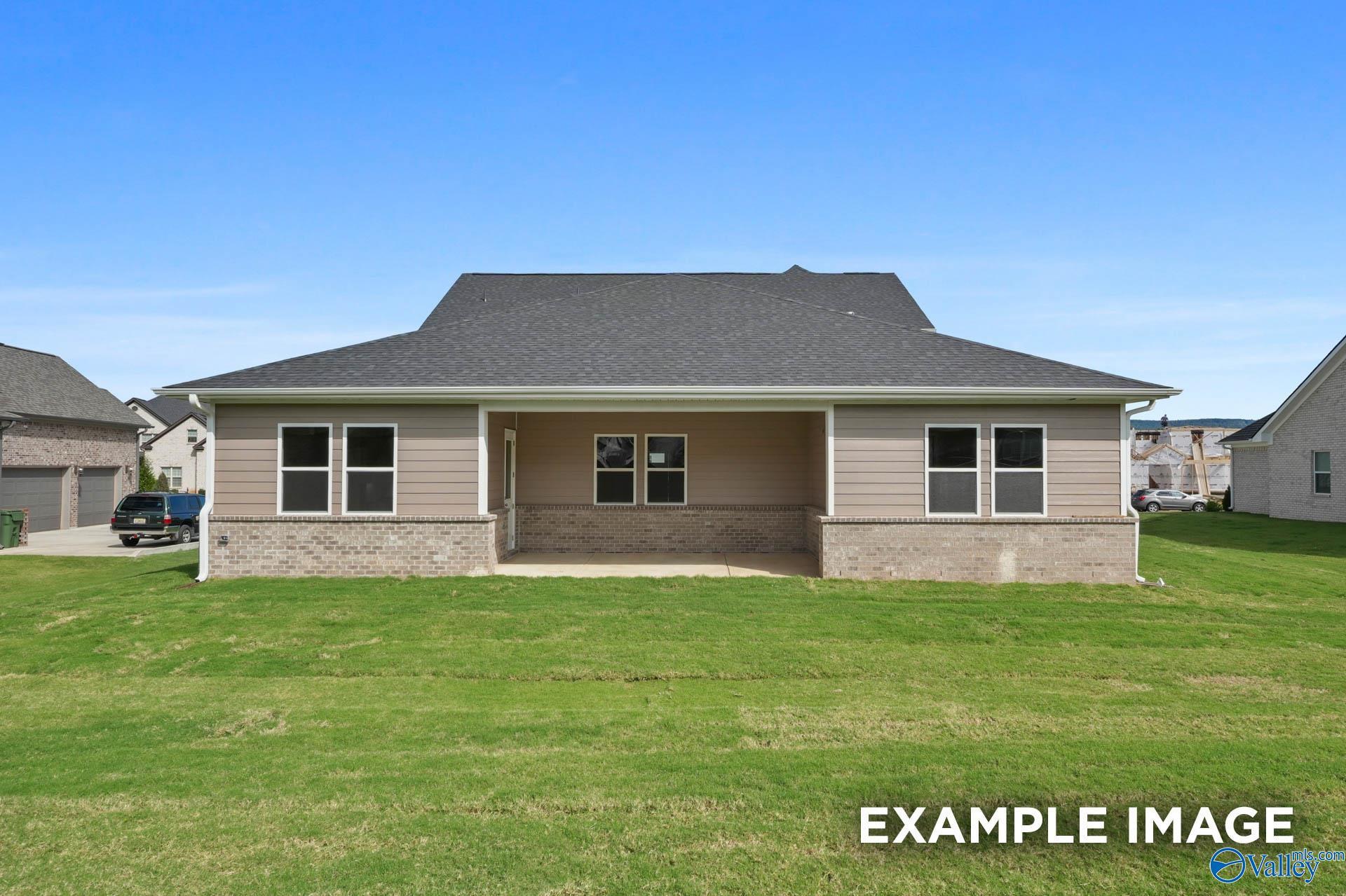 Two-story Haven E home with beige siding, brick base, covered porch, and green lawn in The Meadows at Hampton Cove, Owens Cross Roads, AL