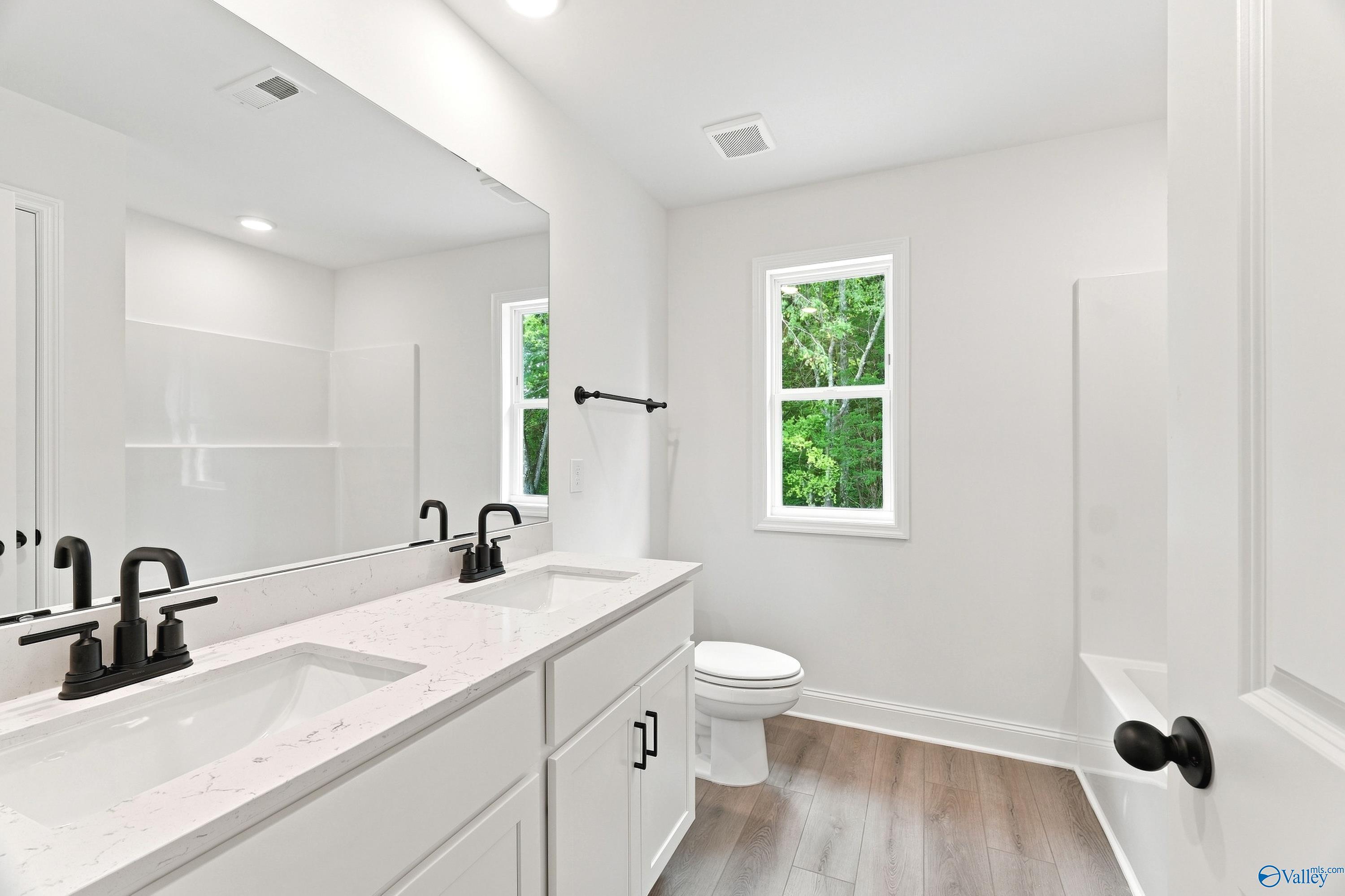 Modern bathroom with double vanity, quartz countertops, and matte black fixtures in The Shelby B at Jaguar Hills, Huntsville.