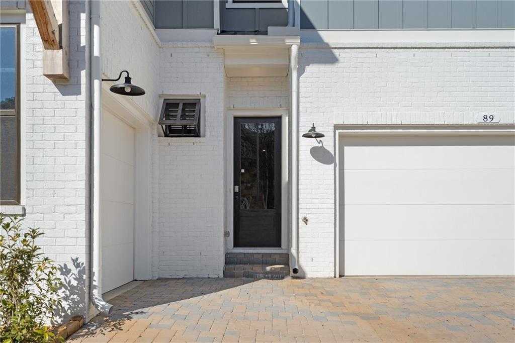 Modern white brick exterior with black front door, lanterns, and 3-car garage in Davidson Homes Seaside A, Woodstock, GA