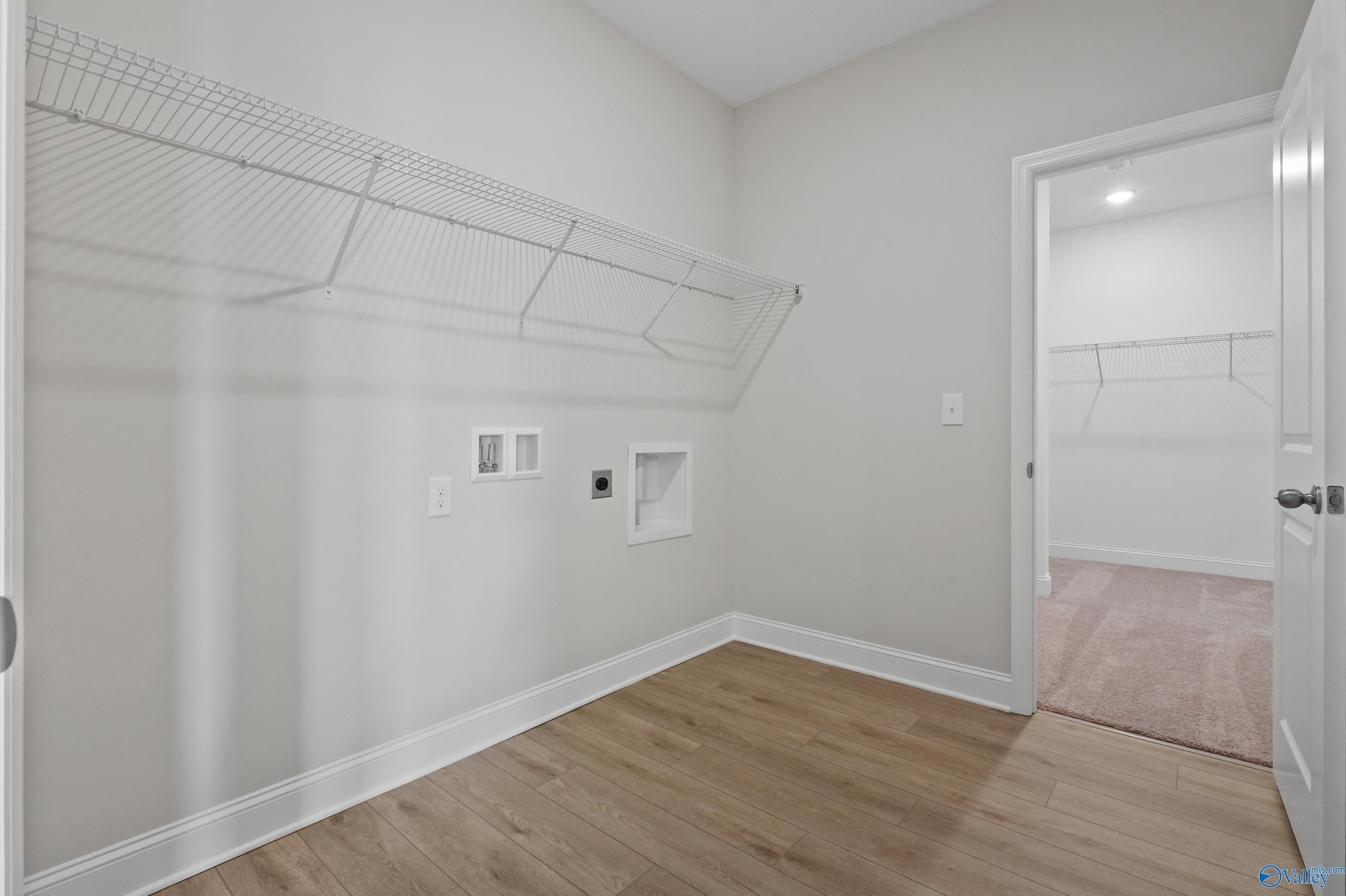 Spacious laundry room with wire shelving, washer-dryer hookups, and utility sink in The Everett floor plan, Davidson Homes, Hazel Green, AL