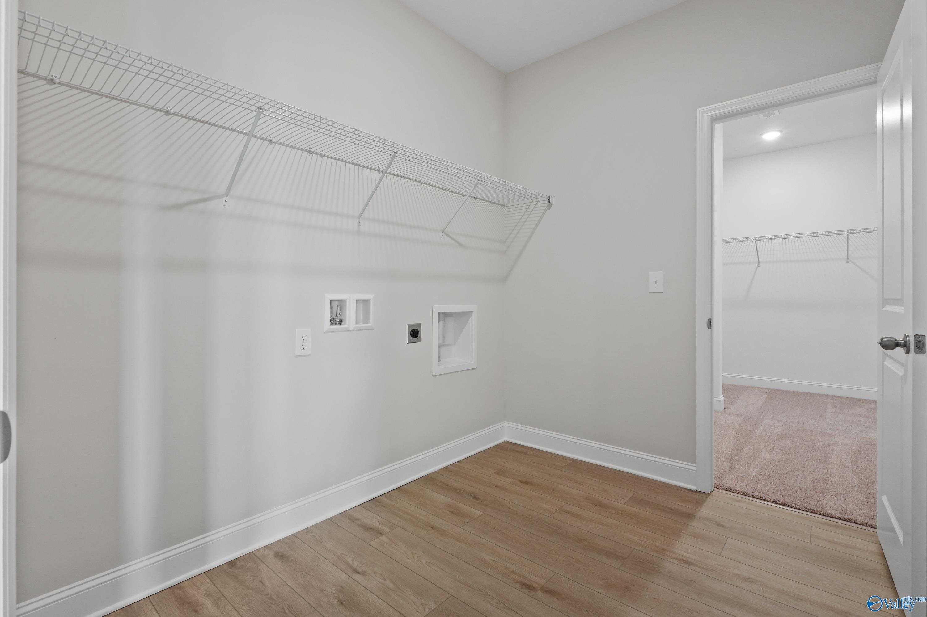 Spacious laundry room with wire shelving, washer-dryer hookups, and utility sink in The Everett floor plan, Davidson Homes, Hazel Green, AL