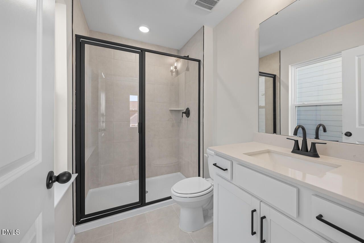 Modern bathroom with glass shower, white vanity and matte black fixtures in Davidson Homes Ashport M plan, Wendell Ridge NC