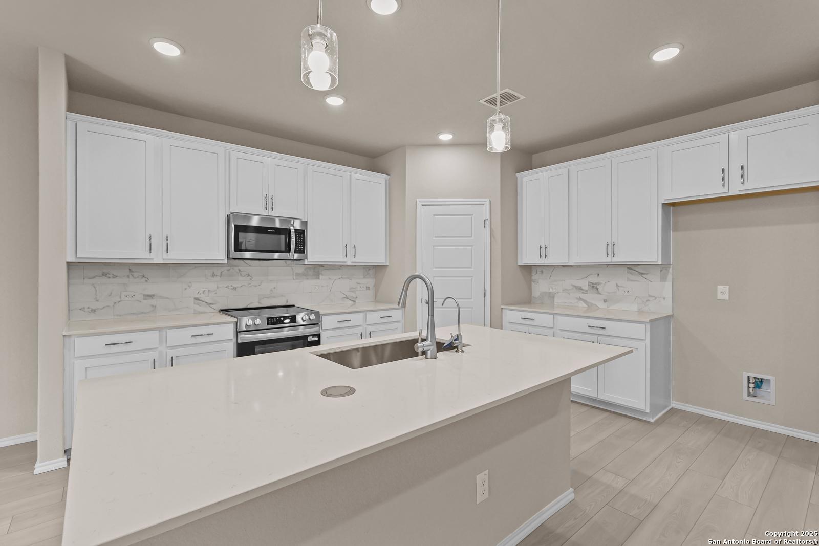 Modern kitchen with white cabinets, quartz countertops, stainless appliances in Davidson Homes The Douglas G, San Antonio