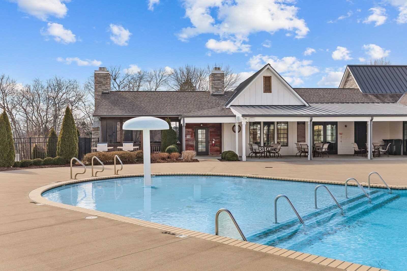Community swimming pool with lounge chairs and umbrella amid homes in Carellton, Gallatin, Tennessee