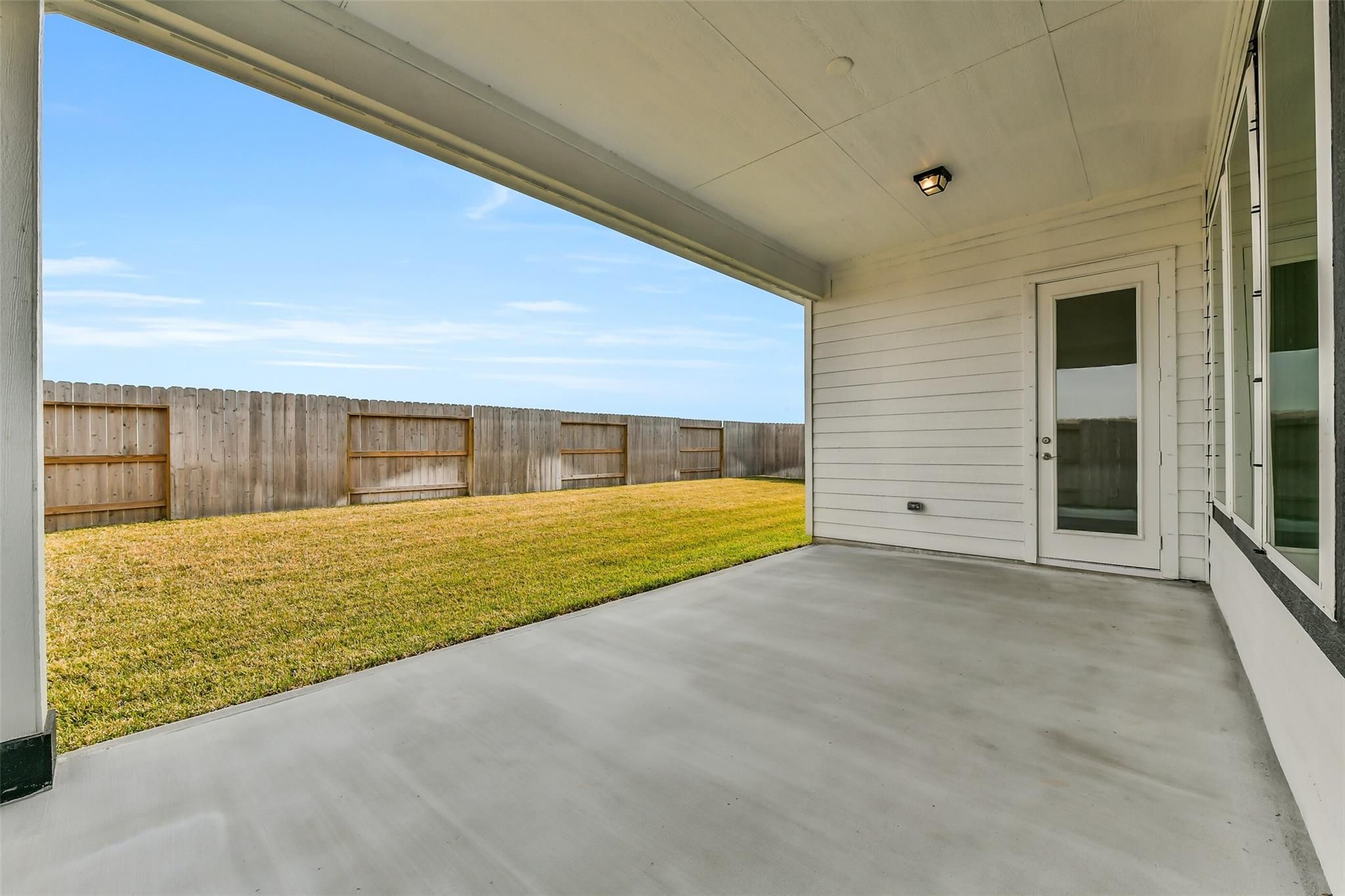Covered back patio with concrete floor overlooking fenced grassy backyard in Davidson Homes The George A, Lago Mar, Texas City, Texas