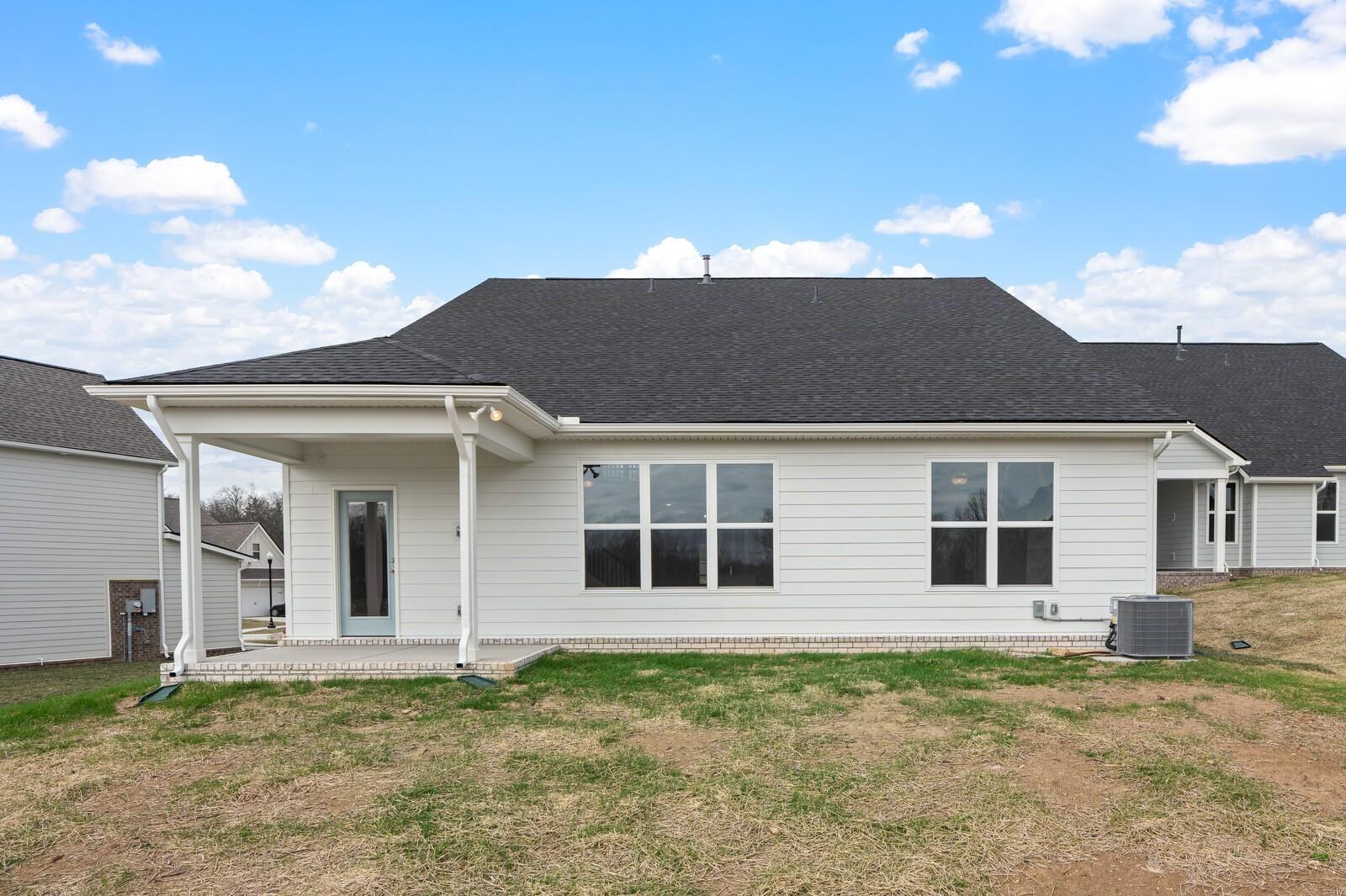 Back view of white two-story Ridgeport home with covered patio, large windows, and grassy yard in Woods Crossing, Gallatin, Tennessee
