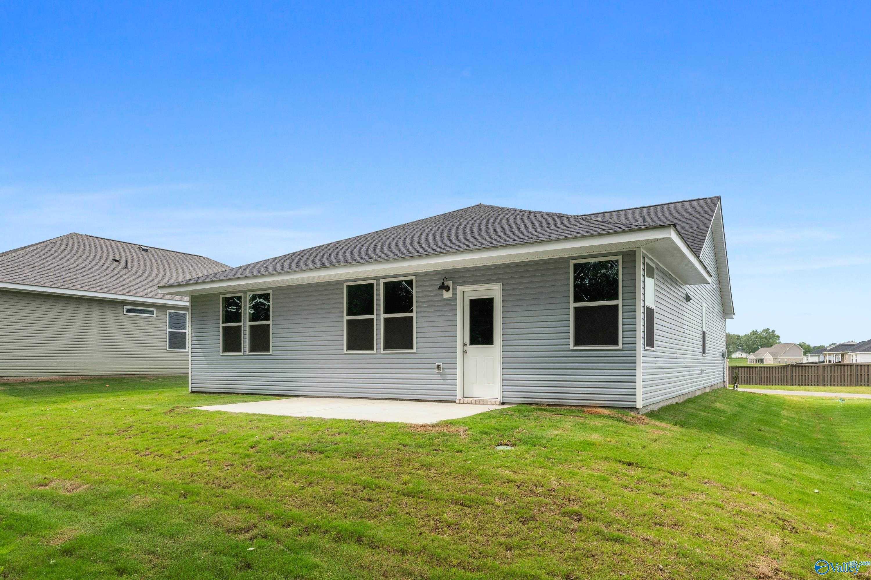 Back view of gray-sided 3-bedroom Davidson Homes Phoenix plan with covered patio, concrete slab, and lush green backyard in Bailey Park, Fayetteville, Tennessee
