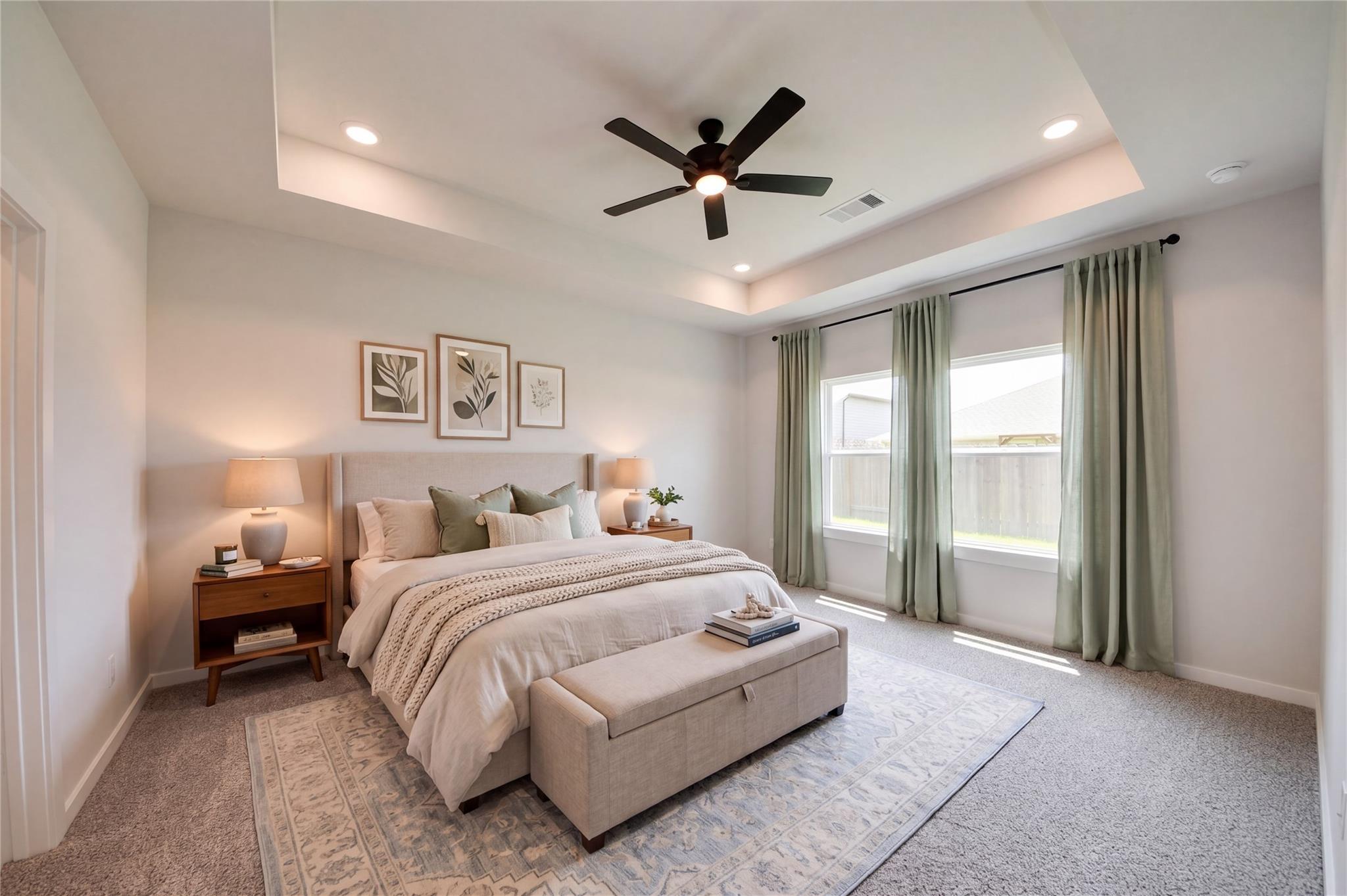 Primary bedroom with tray ceiling and ceiling fan in The Everett C floor plan at River Ranch Meadows in Dayton, Texas.