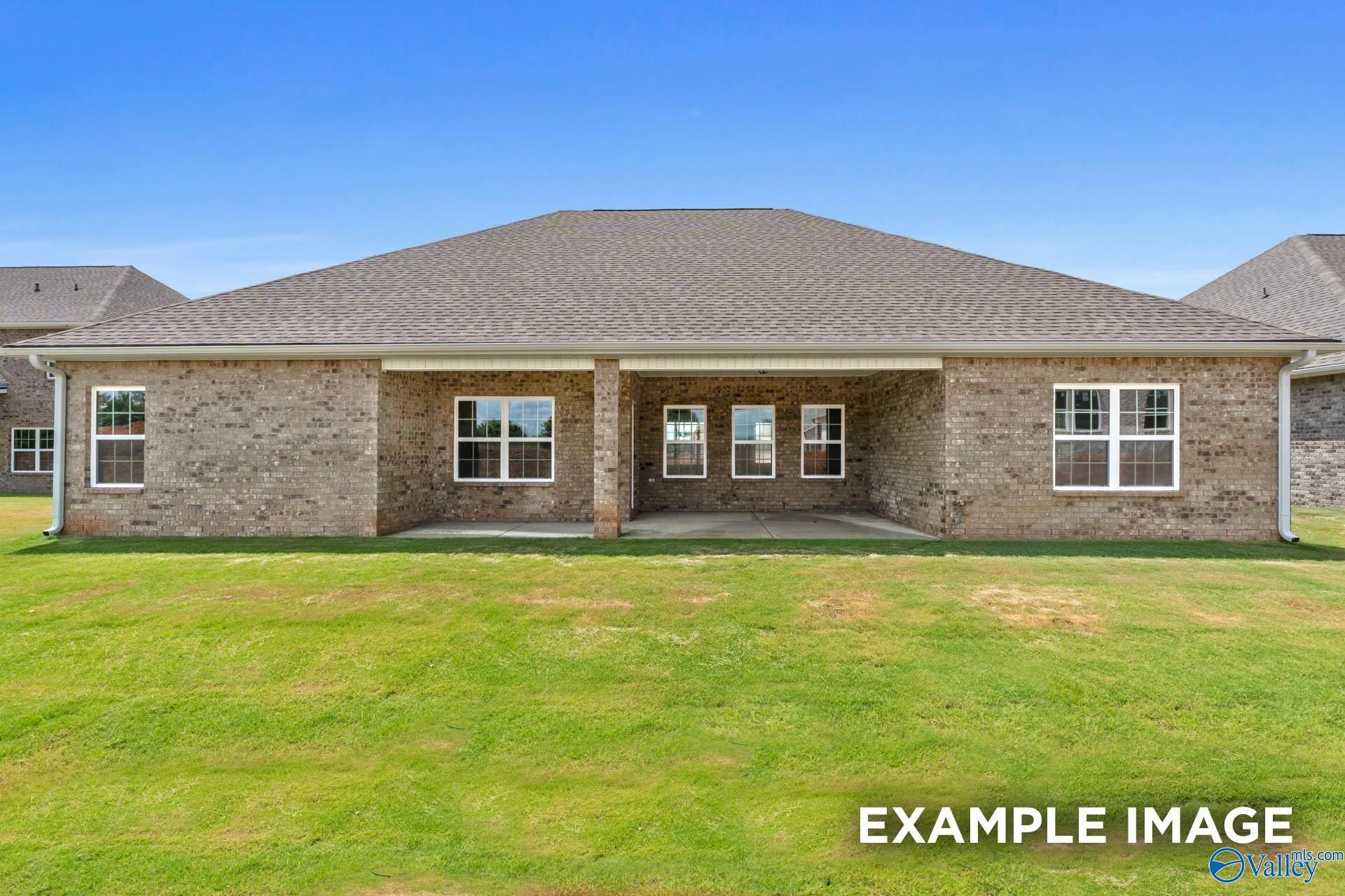 Rear view of brick single-story 4-bedroom home with covered patio, large windows, and grassy backyard in Riverton Preserve, Huntsville, AL