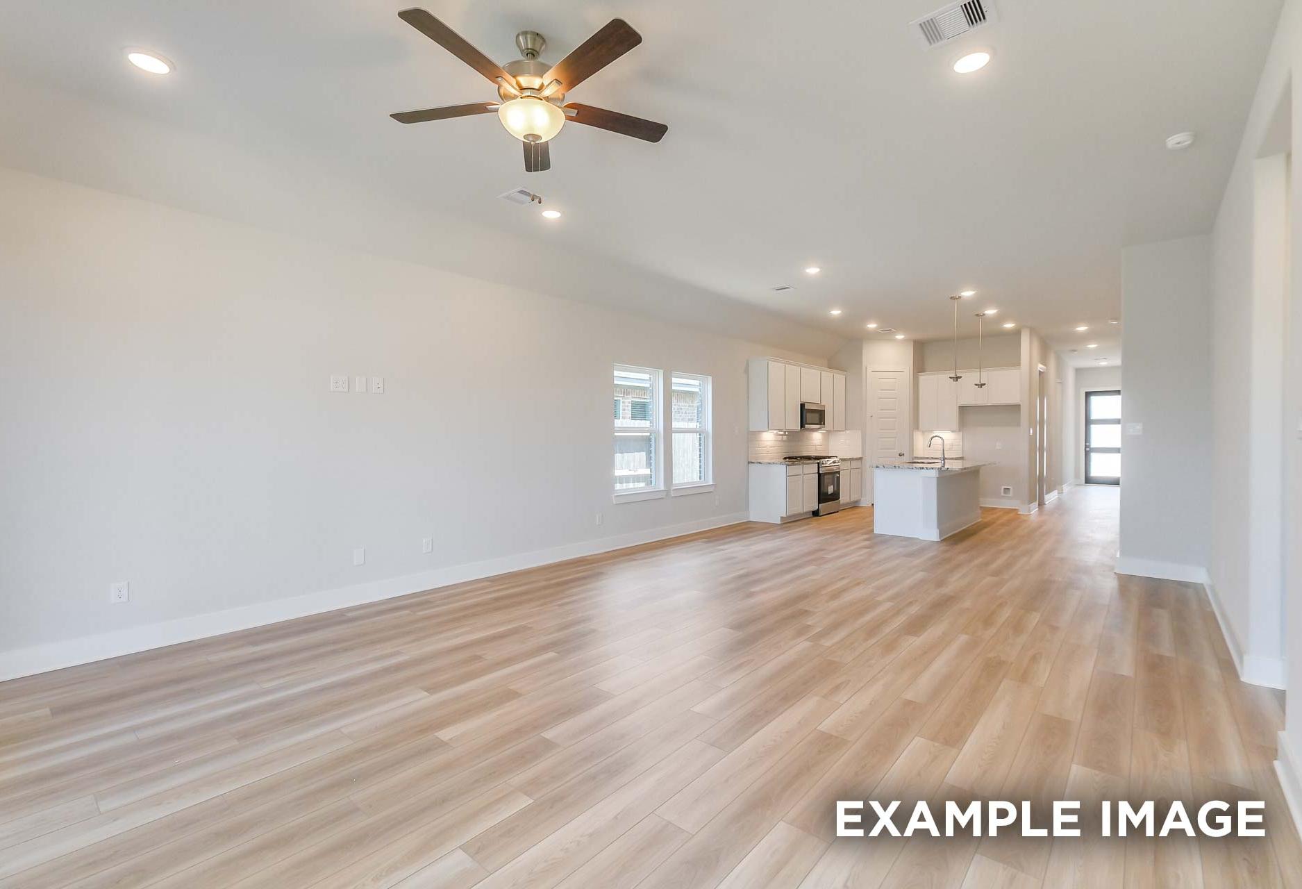 Open-concept living and kitchen in The Luna J home, Davidson Homes Katy TX, featuring white cabinets, large island, ceiling fan, hardwood floors
