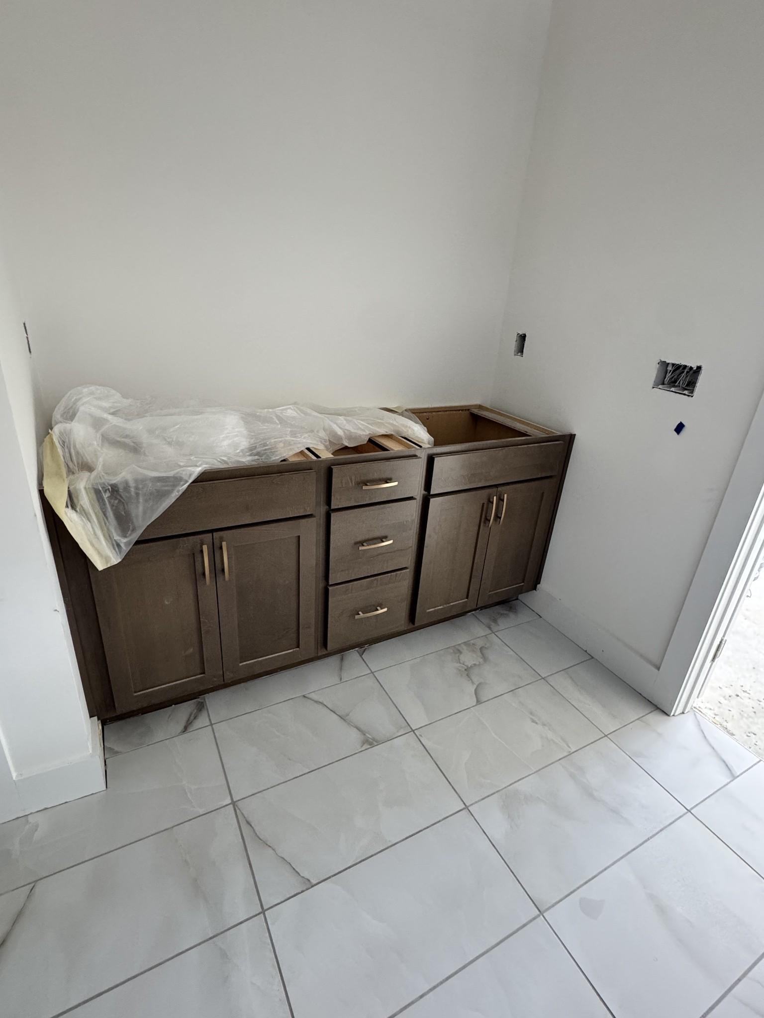 Shaker-style double bathroom vanity with brown cabinets and drawers on veined porcelain tile in Davidson Homes Prairie C, Gallatin TN